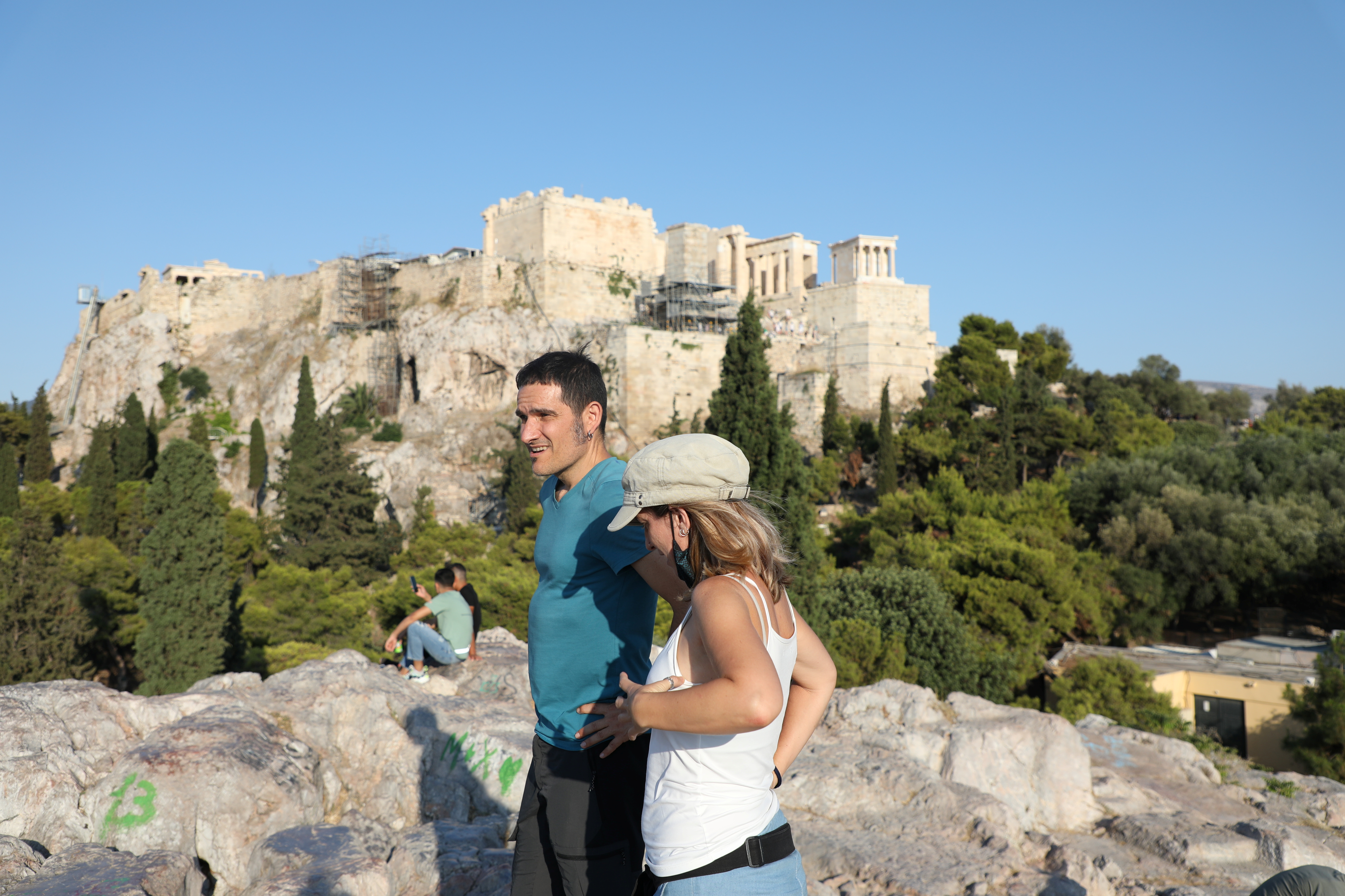 People visit the Areios Pagos hill with Acropolis in the background in Athens