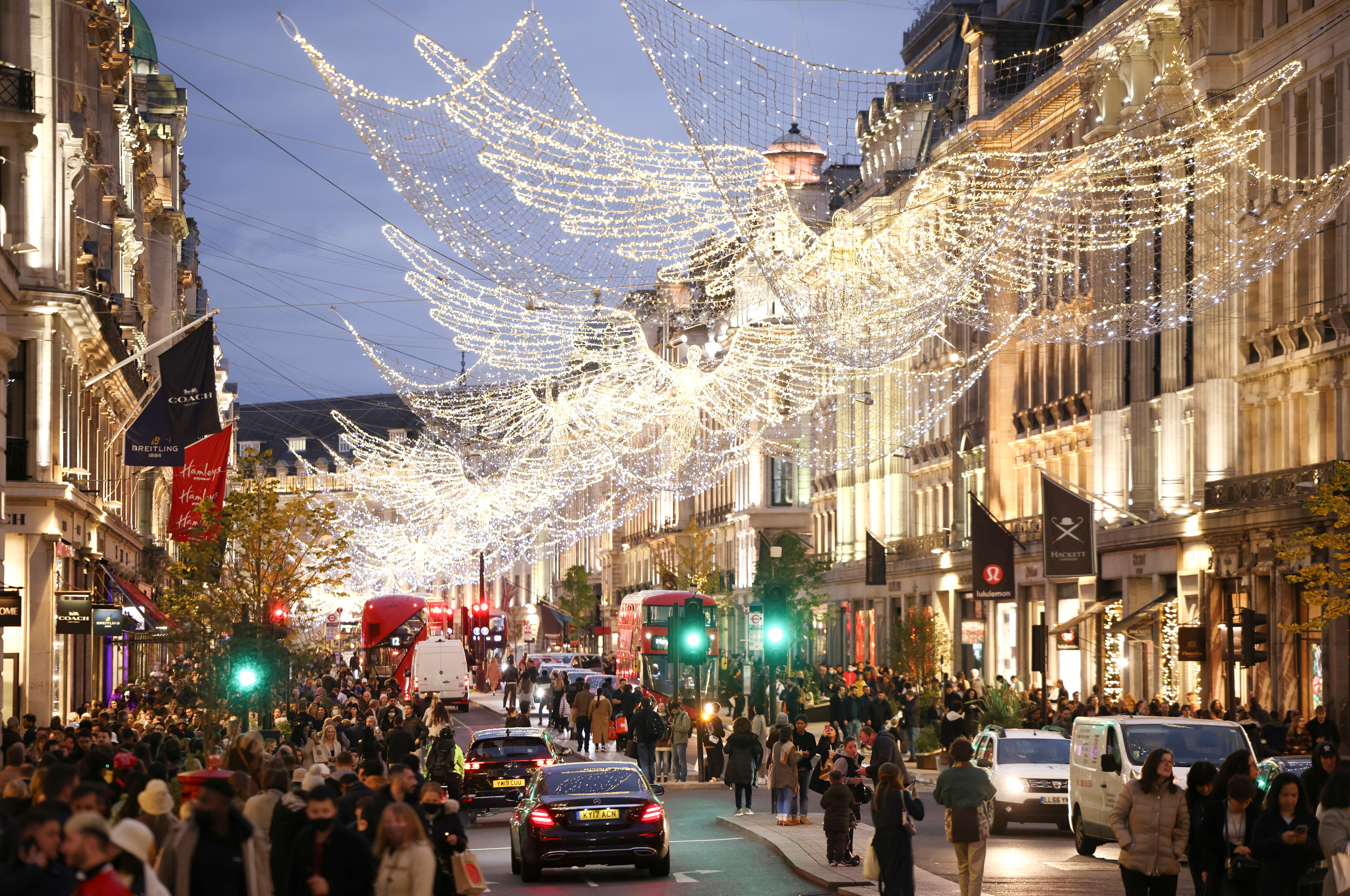 People walk along Regent Street illuminated with Christmas lights in London