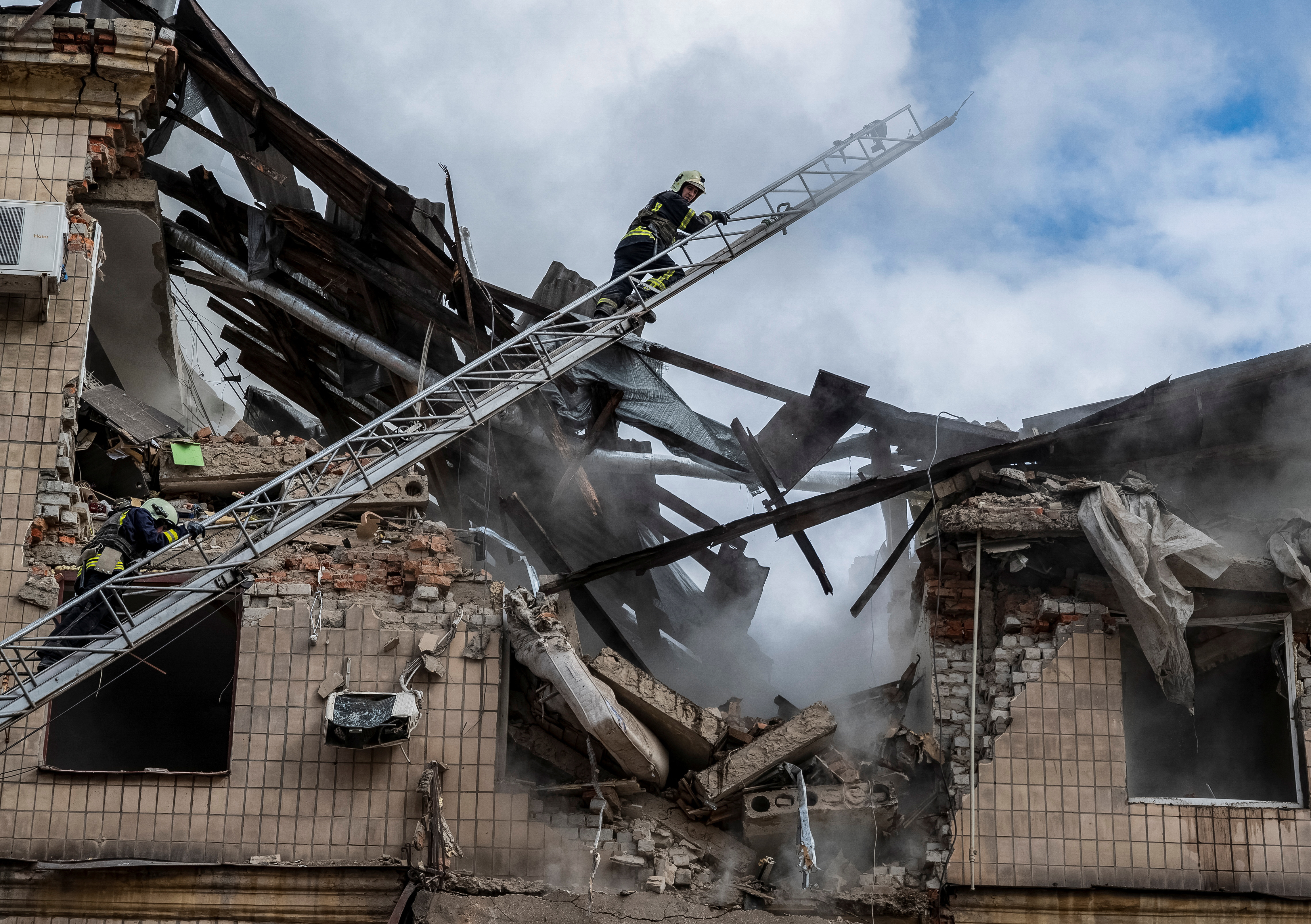 Firefighters work at the site of a residential building hit by a Russian military strike in Kharkiv