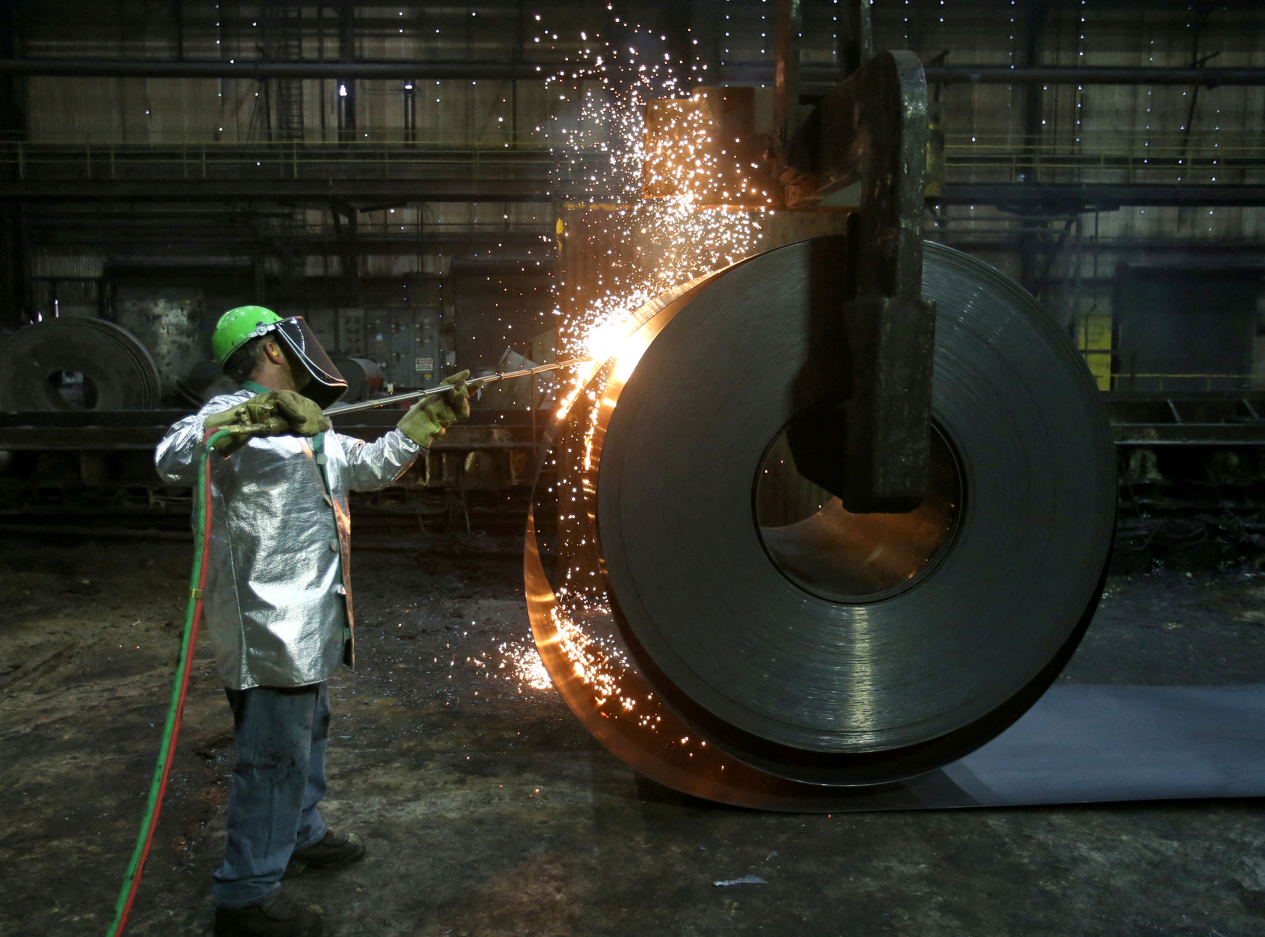 A worker cuts a piece from a steel coil at the Novolipetsk Steel PAO steel mill in Farrell