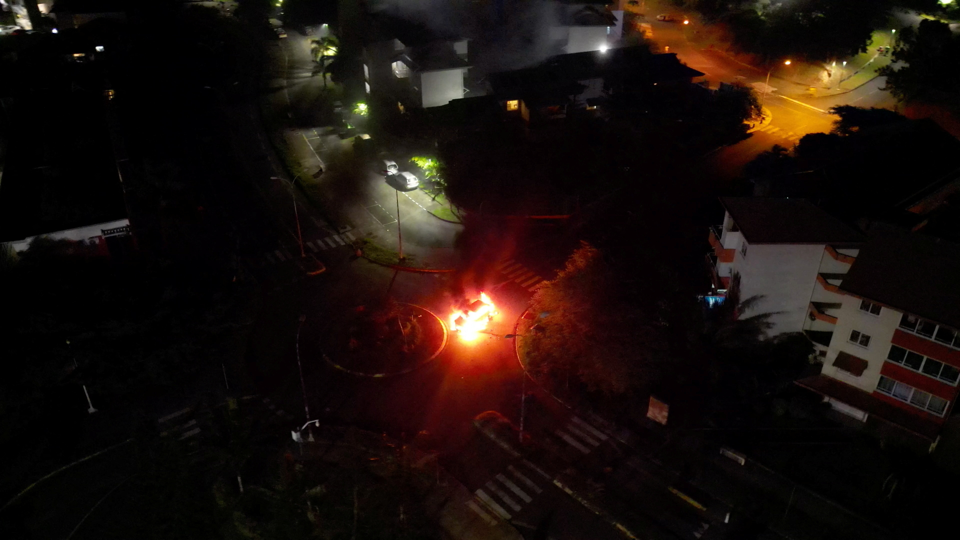 A car is seen lit on fire amid protests in Noumea