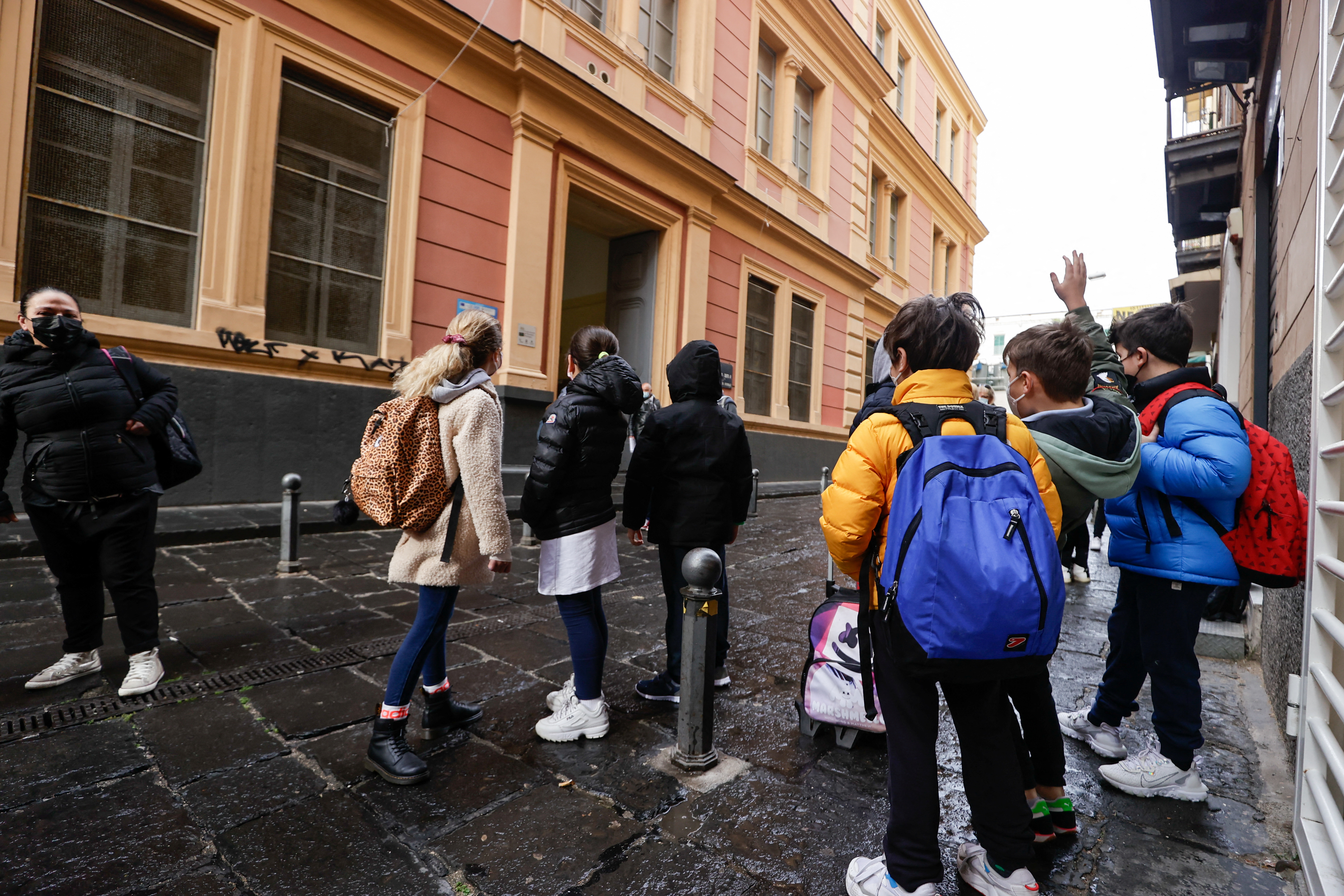 Children stand outside a school as the town is downgraded from a red to an orange zone, after weeks of tight restrictions to fight the coronavirus disease (COVID-19) outbreak, in Naples, Italy, April 19, 2021. REUTERS/Ciro de Luca