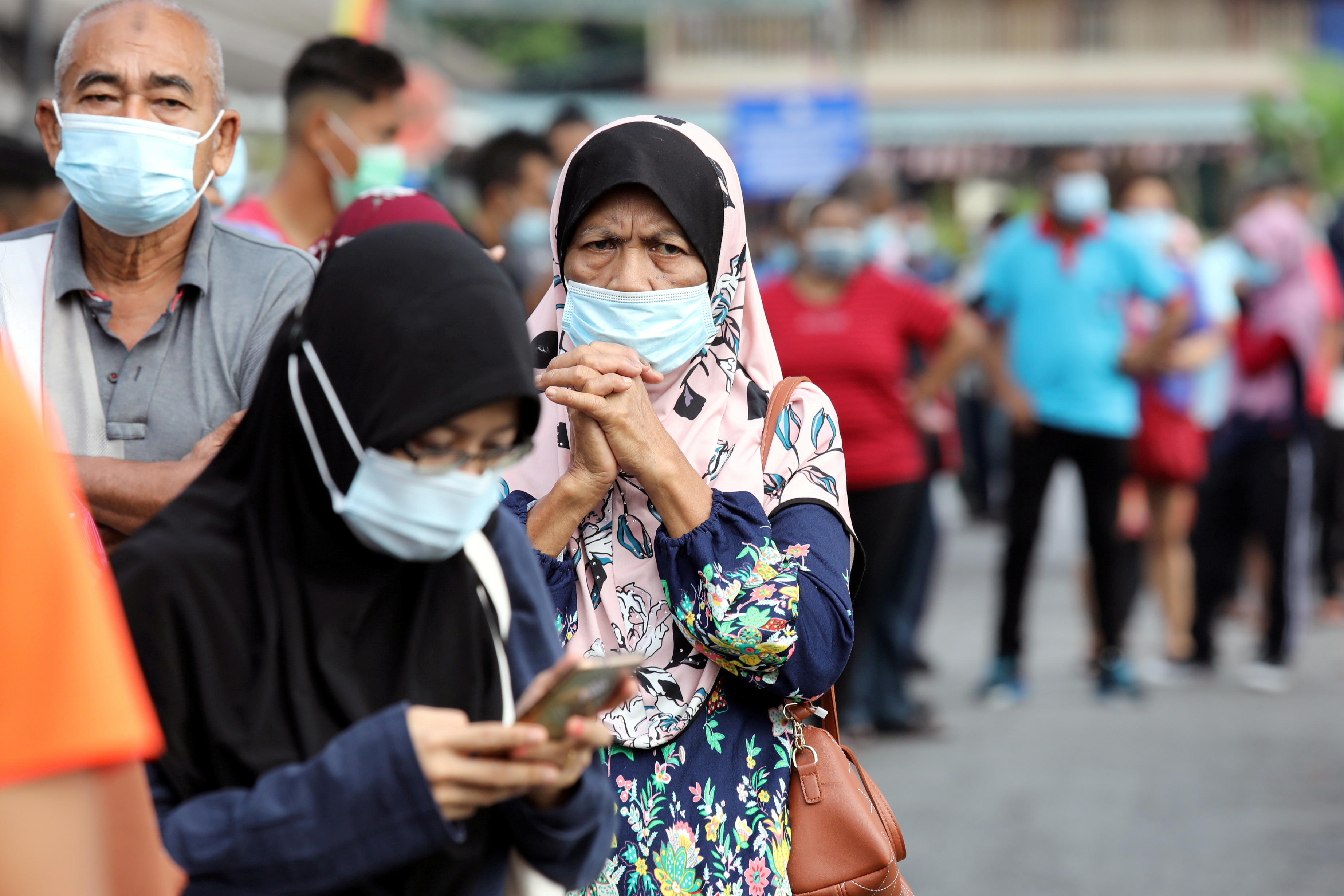 People wait in line to be tested for the coronavirus disease (COVID-19) at a testing station in Klang