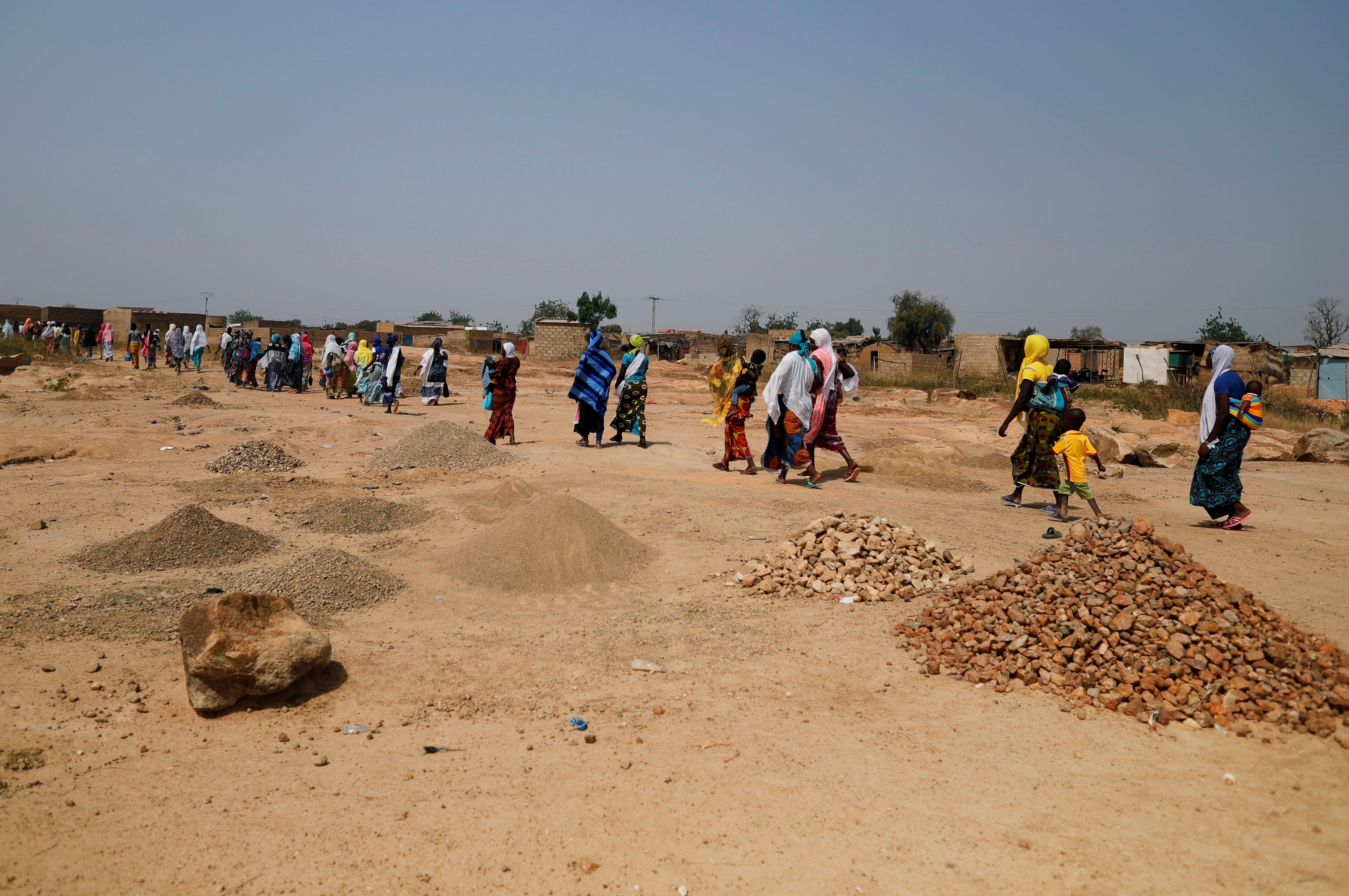 Women who fled from attacks of armed militants in Sahel region of Soum walk at an informal camp for displaced people on the outskirts of Ouagadougou,