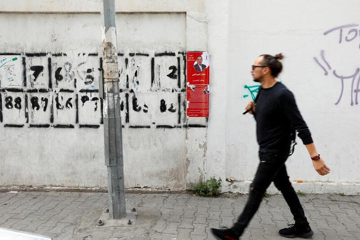 A man walks past campaign posters ahead of the parliamentary election in Tunis