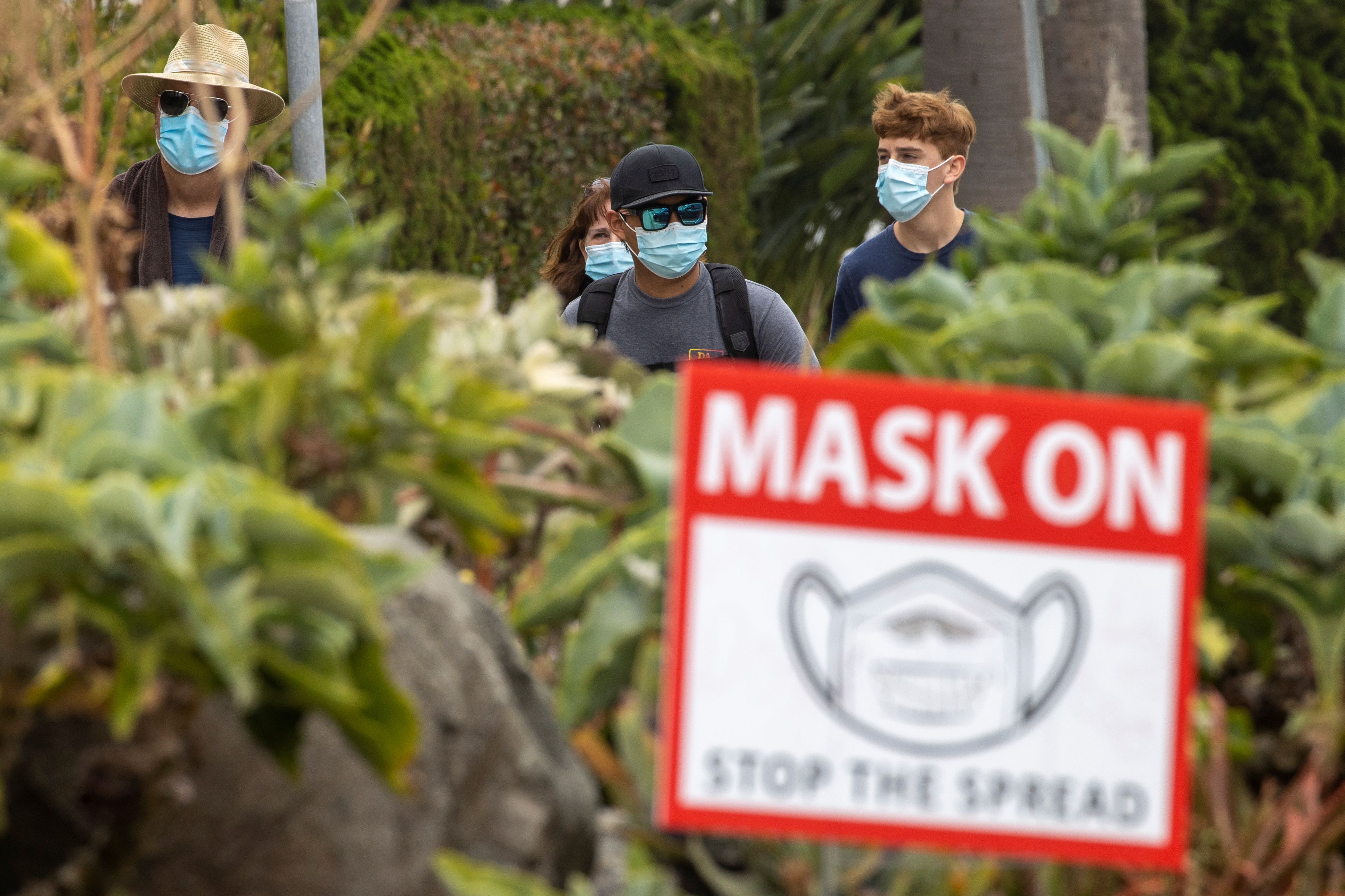 People wear masks as they walk along the side walk during the outbreak of the coronavirus disease in California