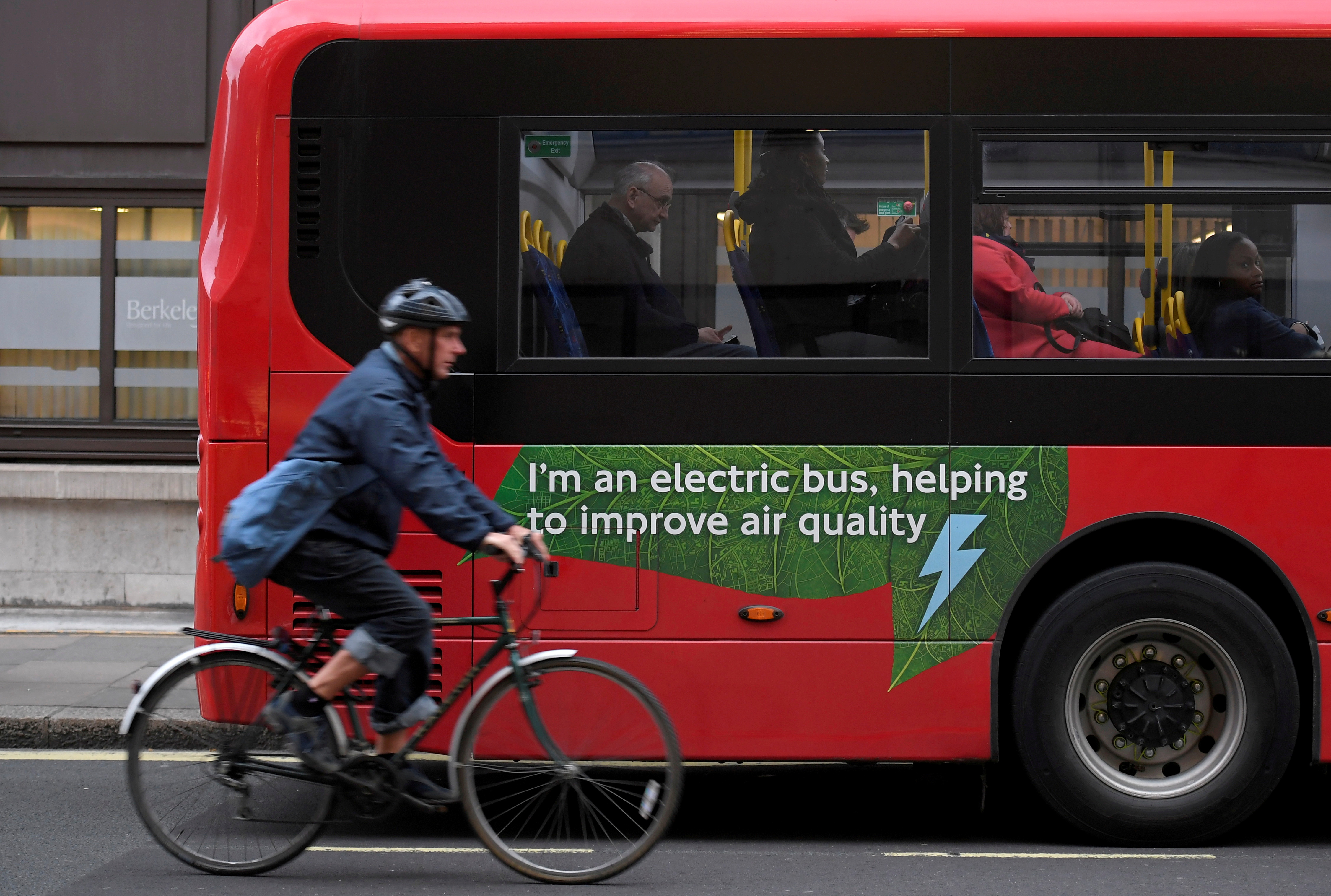 A cyclist rides past an electric public bus on the day that Mayor of London Sadiq Khan outlined plans to place a levy on the most polluting vehicles in London, Britain