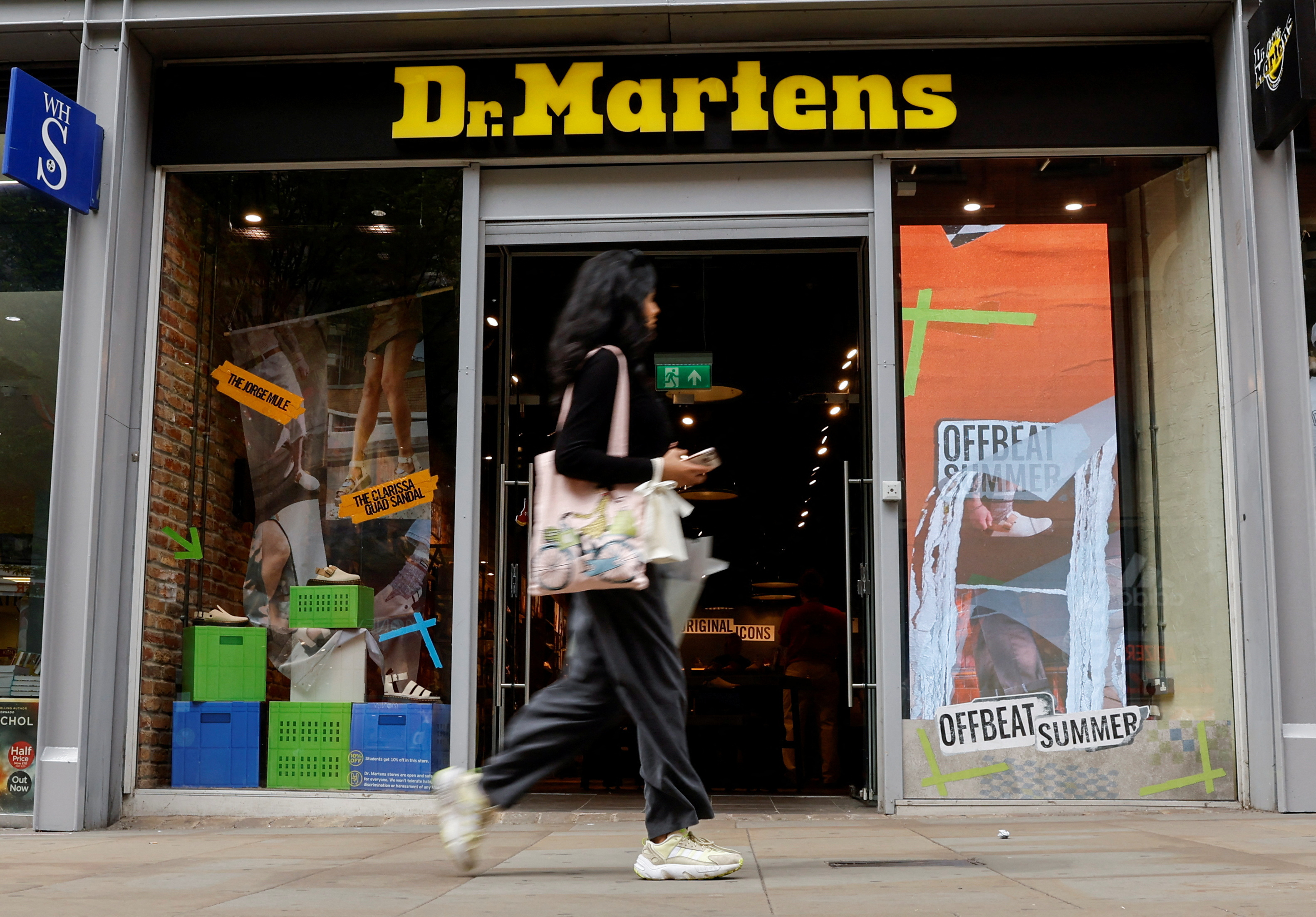 A woman walks past a Dr. Martens store in Manchester