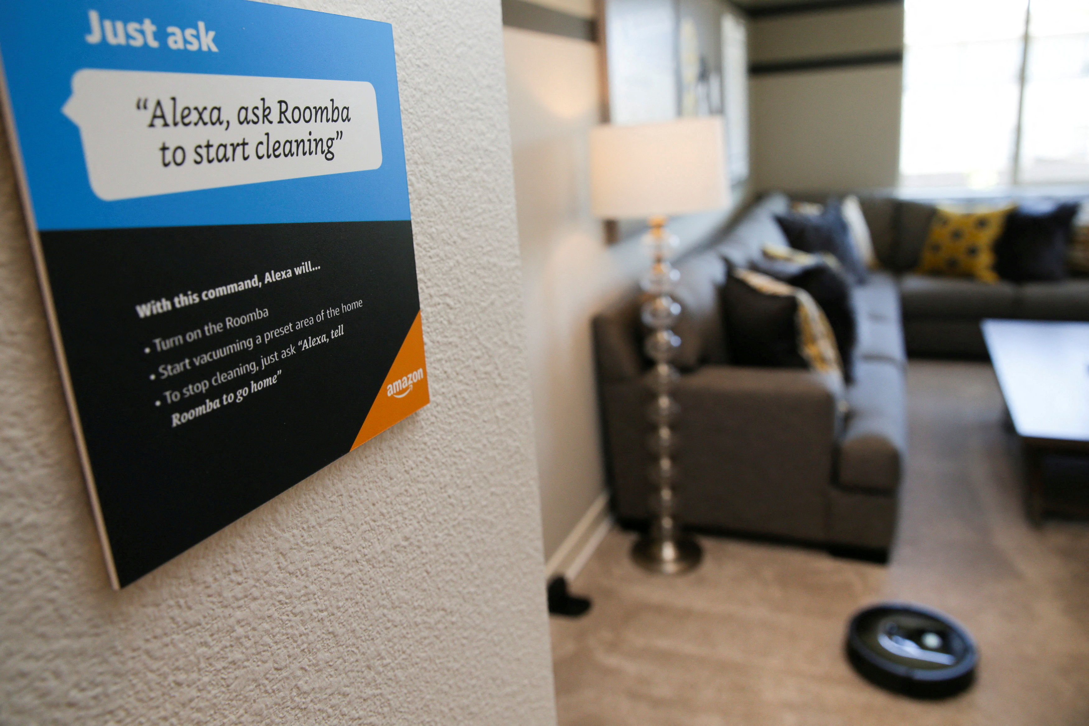 Prompts on how to use Amazon's Alexa personal assistant are seen as a wifi-equipped Roomba begins cleaning a room in an Amazon ‘experience center’  in Vallejo