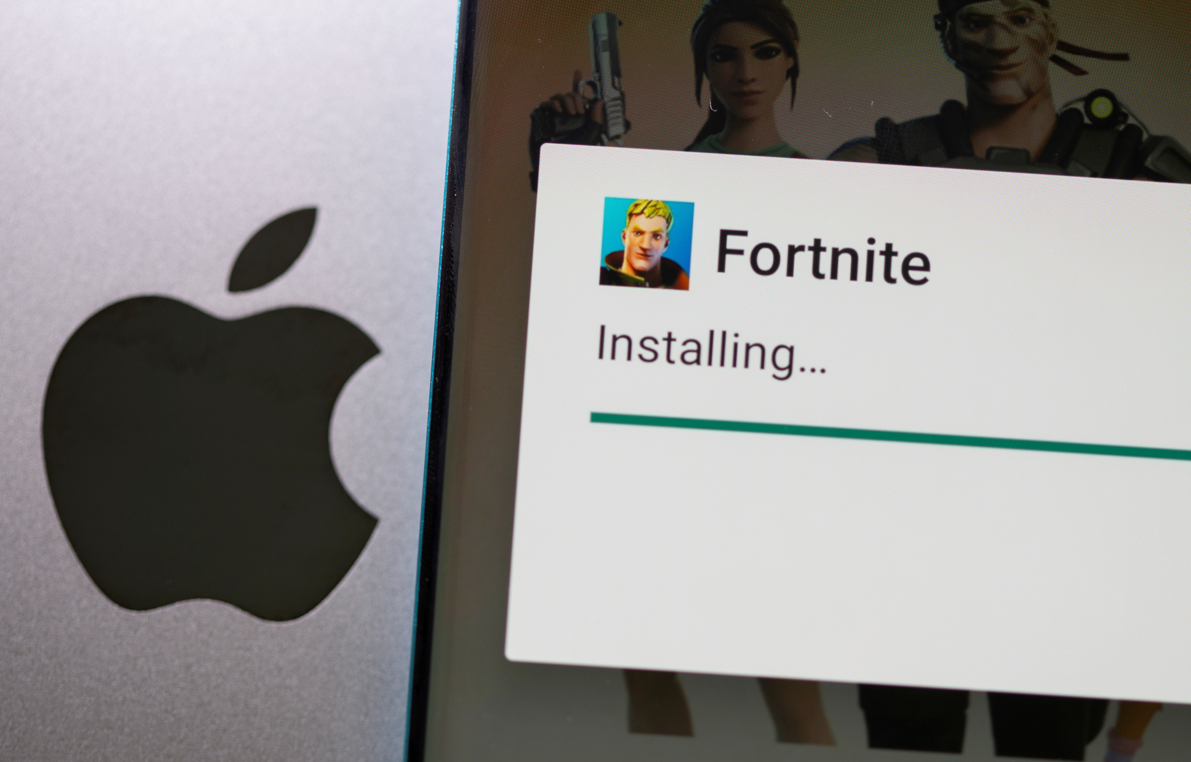 Fortnite installing on Android is seen in front of Apple logo in this illustration