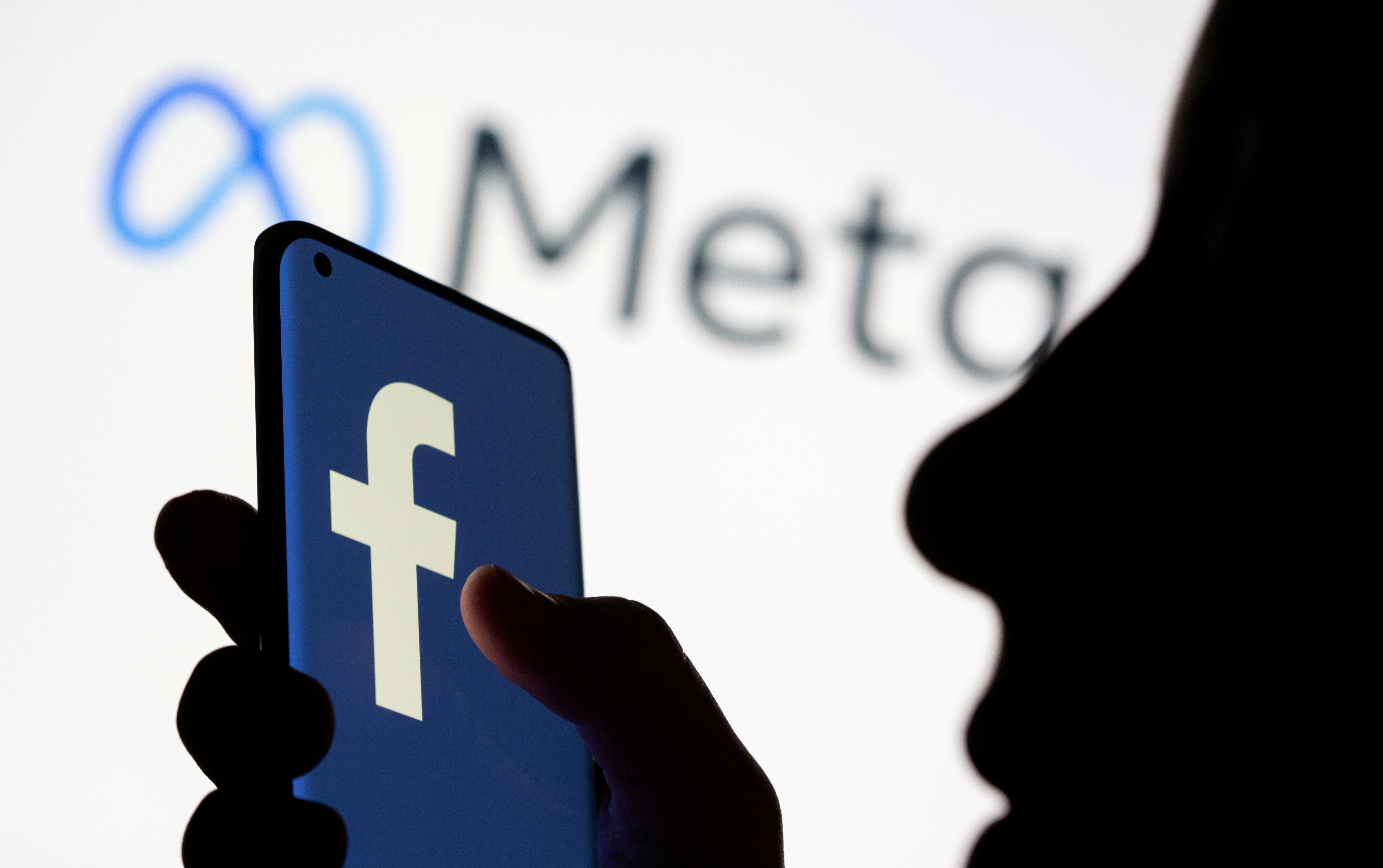 Woman holds smartphone with Facebook logo in front of  Facebook's new rebrand logo Meta in this illustration picture taken October 28, 2021. REUTERS/Dado Ruvic