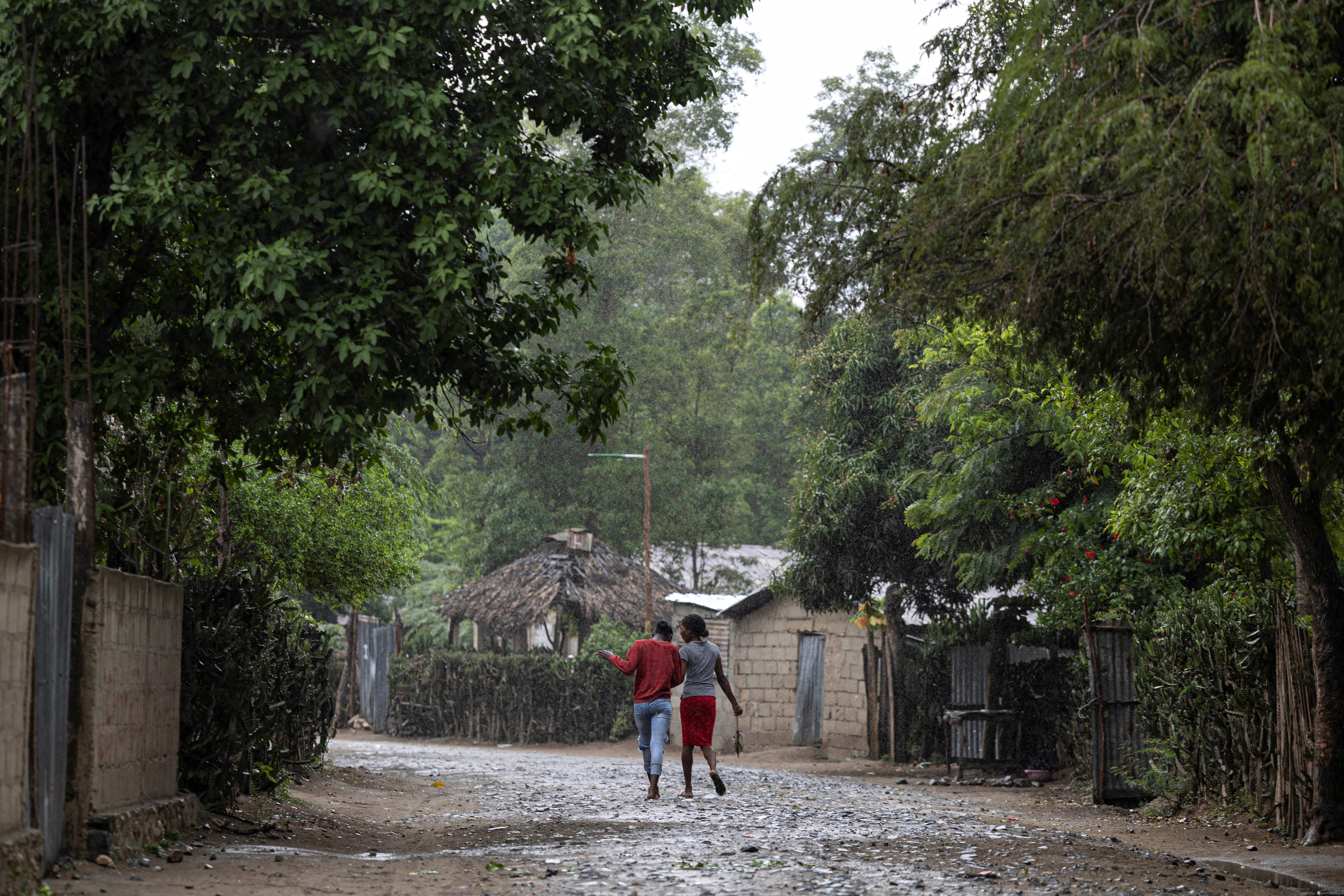 Women walk under the rain in the Malfety neighborhood of Fort Liberte