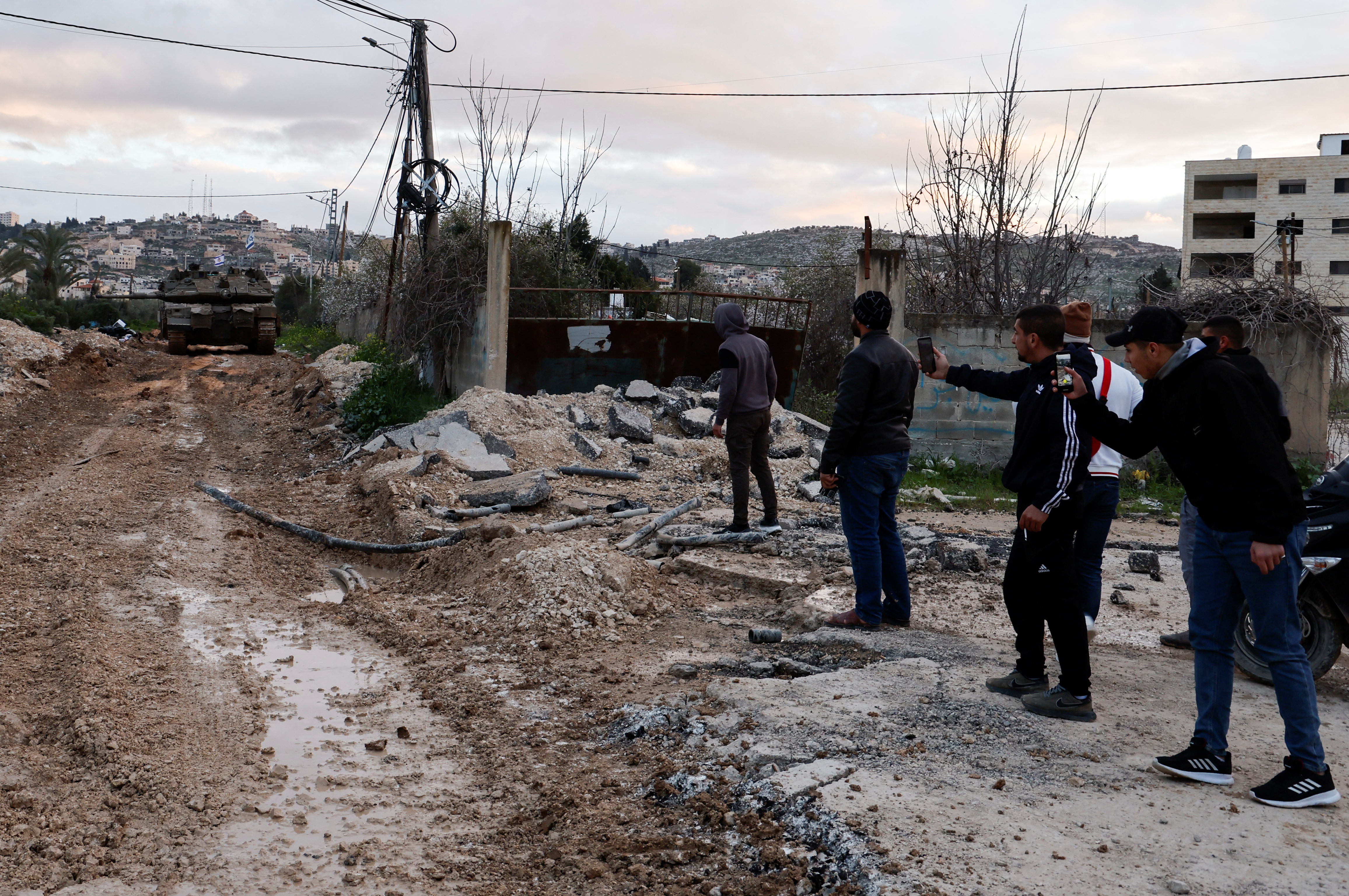 Photograph depicting the aftermath of an Israeli military operation in the Jenin refugee camp in the West Bank, showing damaged buildings and civilians searching for survivors.
