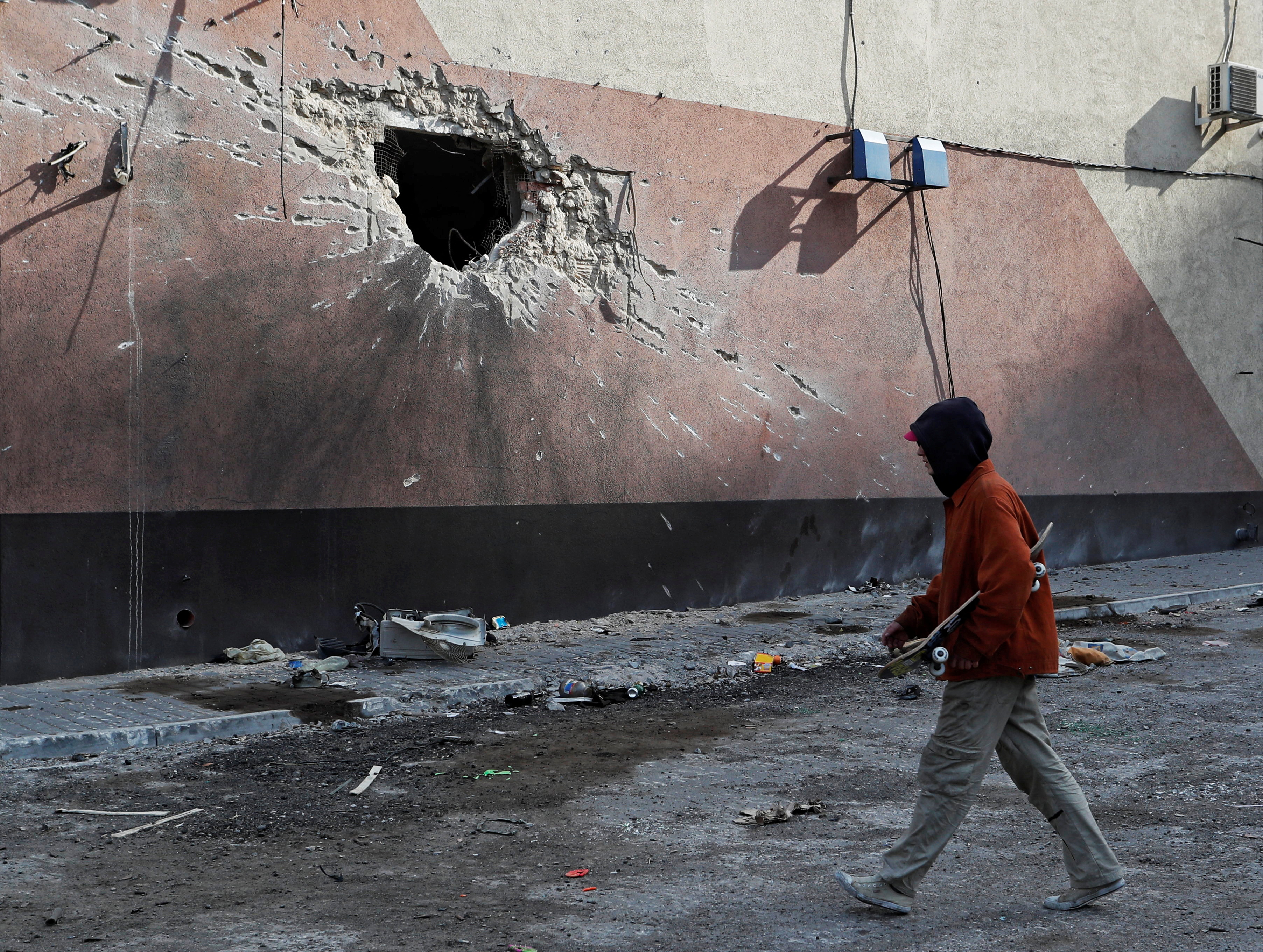 A local resident walks past a damaged building in Mariupol