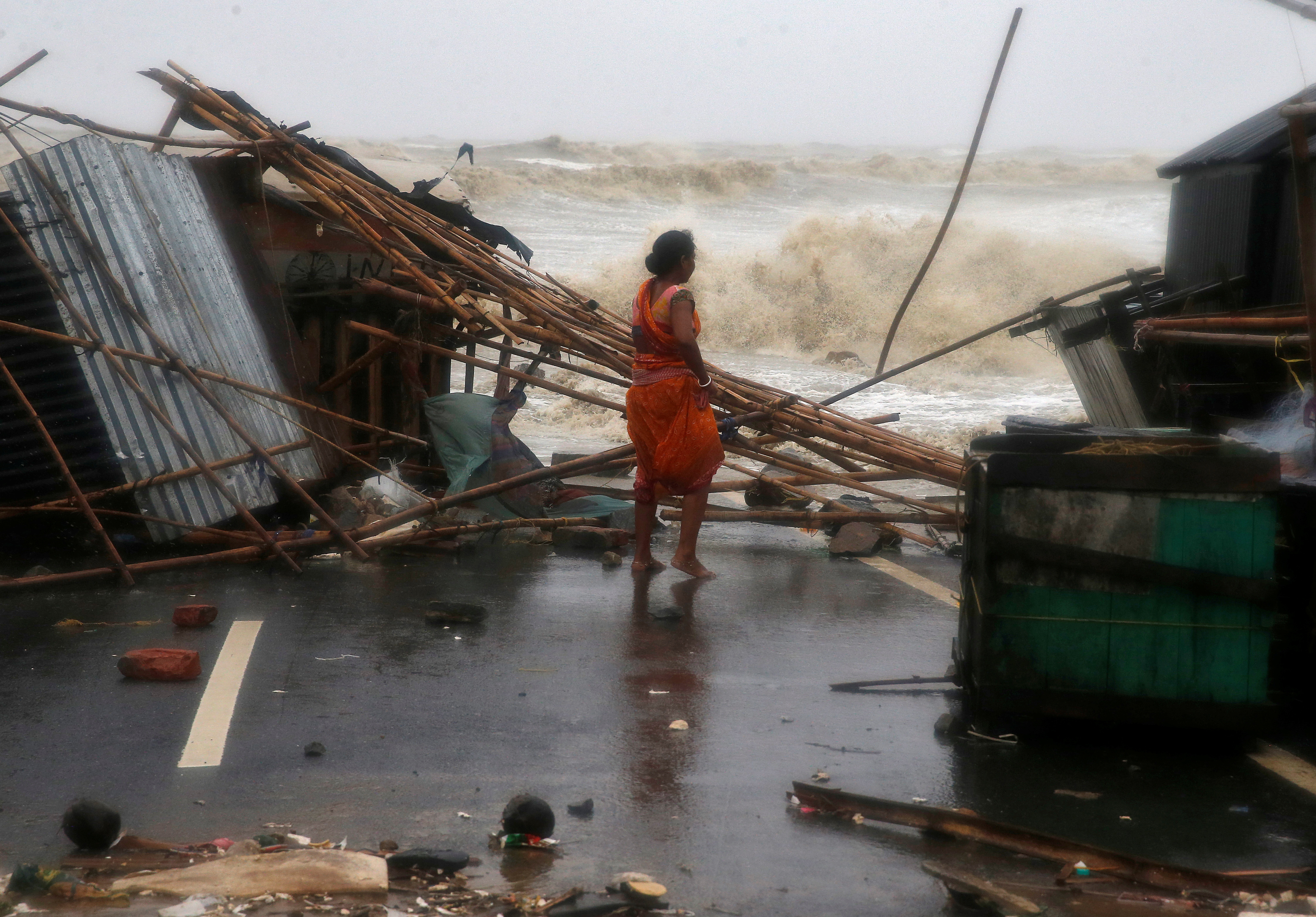 A woman stands next to her stall damaged by heavy winds at a shore ahead of Cyclone Yaas in Bichitrapur