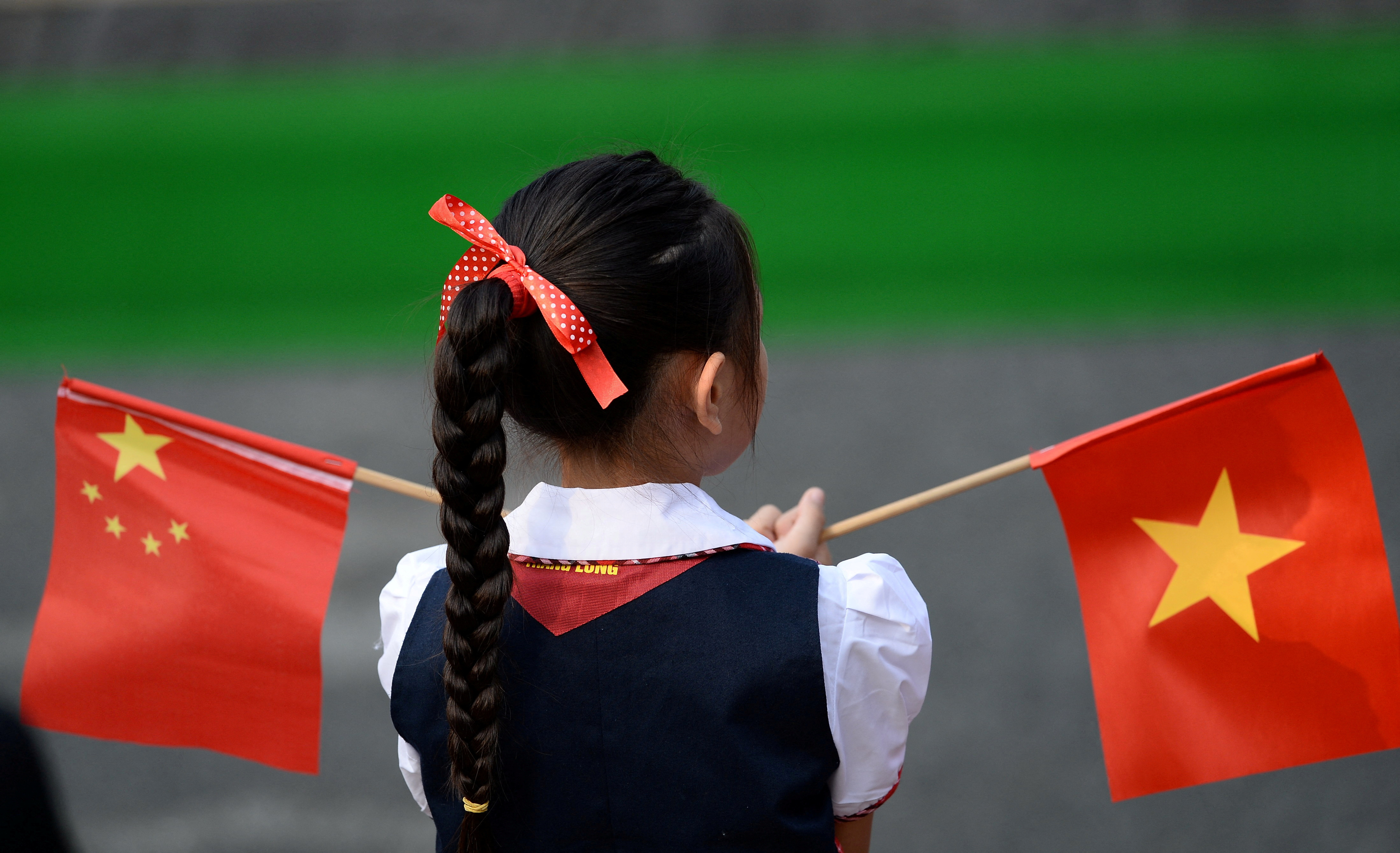 A Vietnamese pupil holds Vietnamese and Chinese flags at the Presidential Palace in Hanoi
