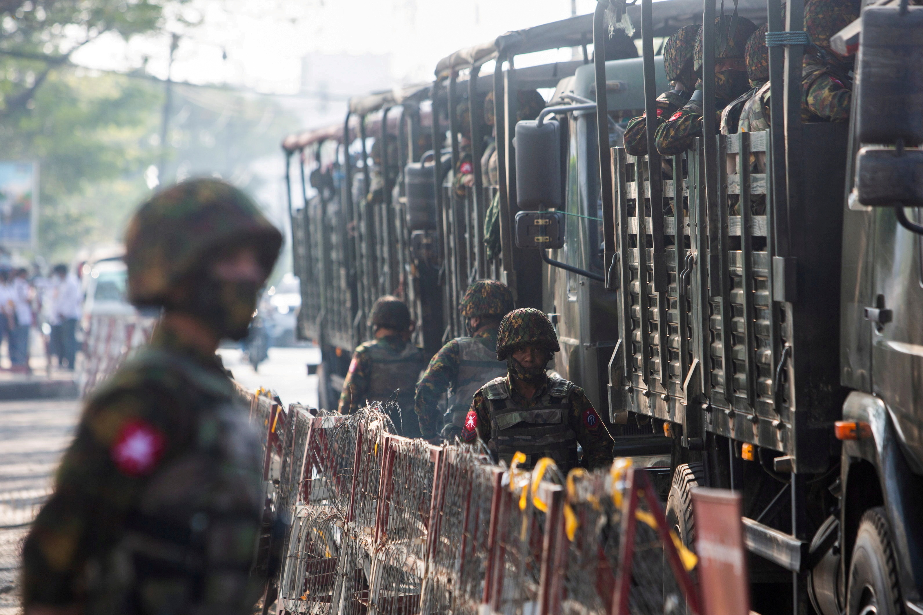 Soldiers stand next to military vehicles as people gather to protest against the military coup, in Yangon