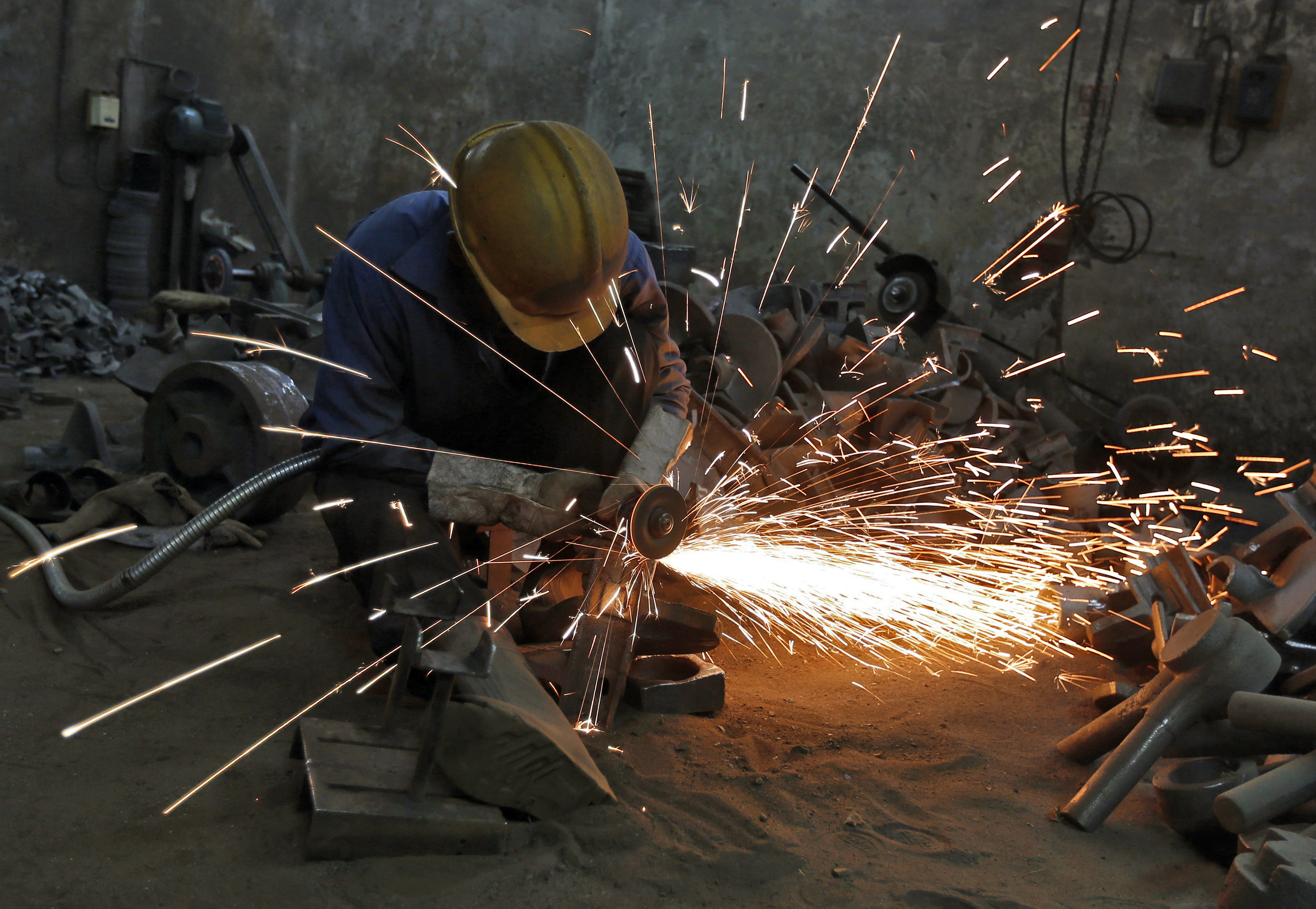 A worker grinds a metal shaft metal on outskirts of Ahmedabad