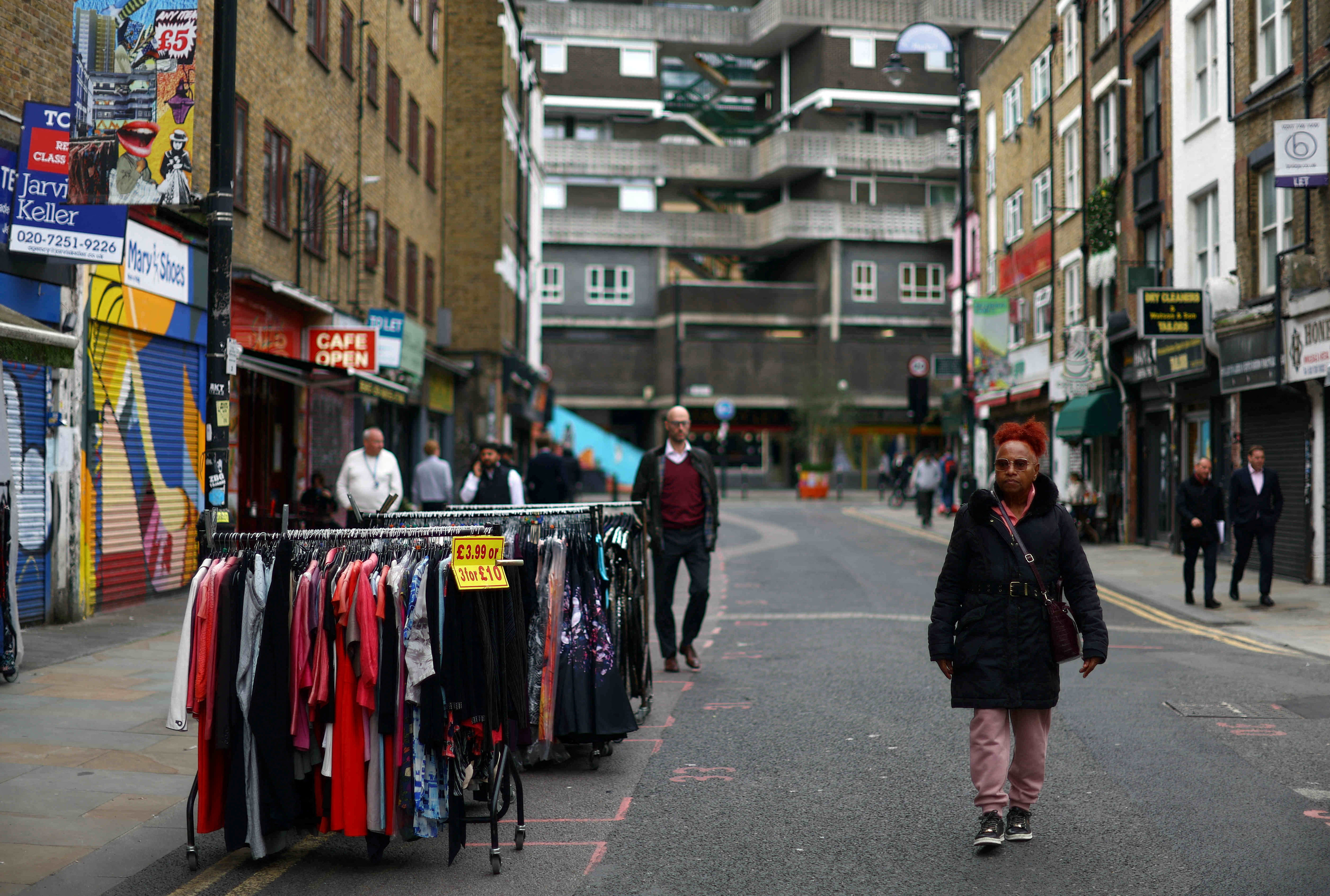 A woman walks past a clothes rail with items for sale in London