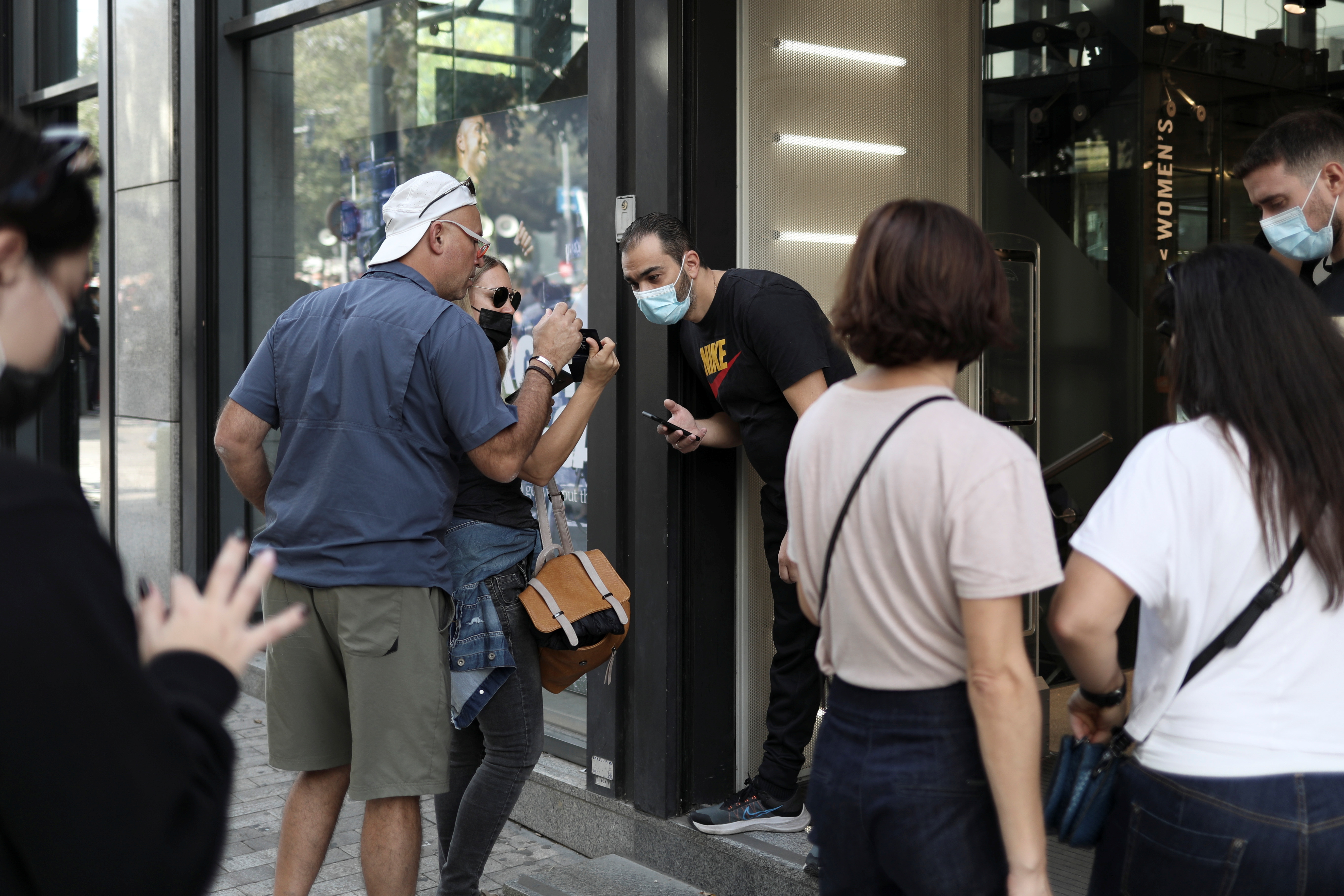 Shop employee checks customers’ vaccination certificates against the coronavirus disease (COVID-19), as the government imposed further measures for unvaccinated citizens, in Athens