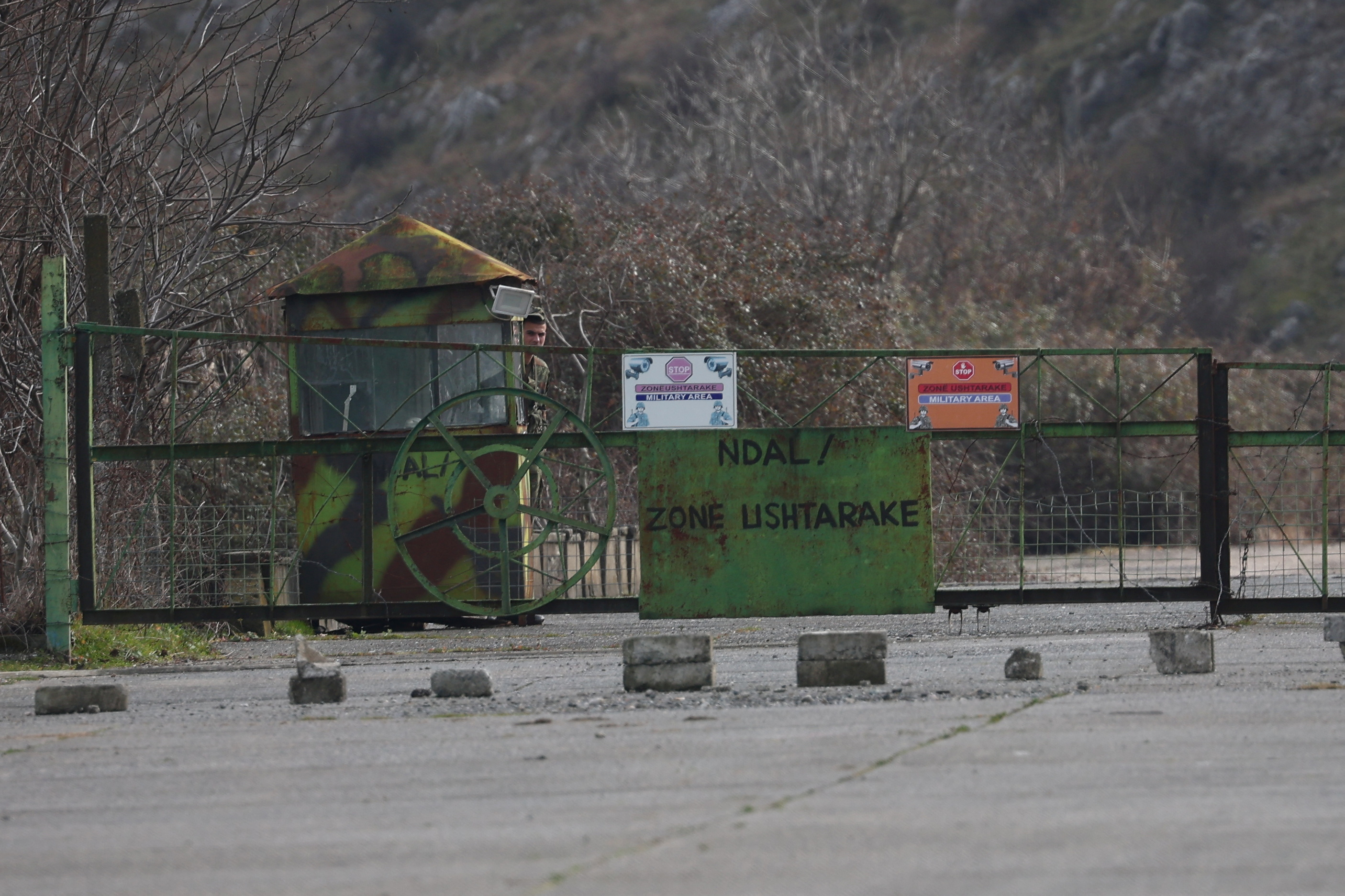 A soldier looks on at a checkpoint at a military base, in Gjader emigrantë