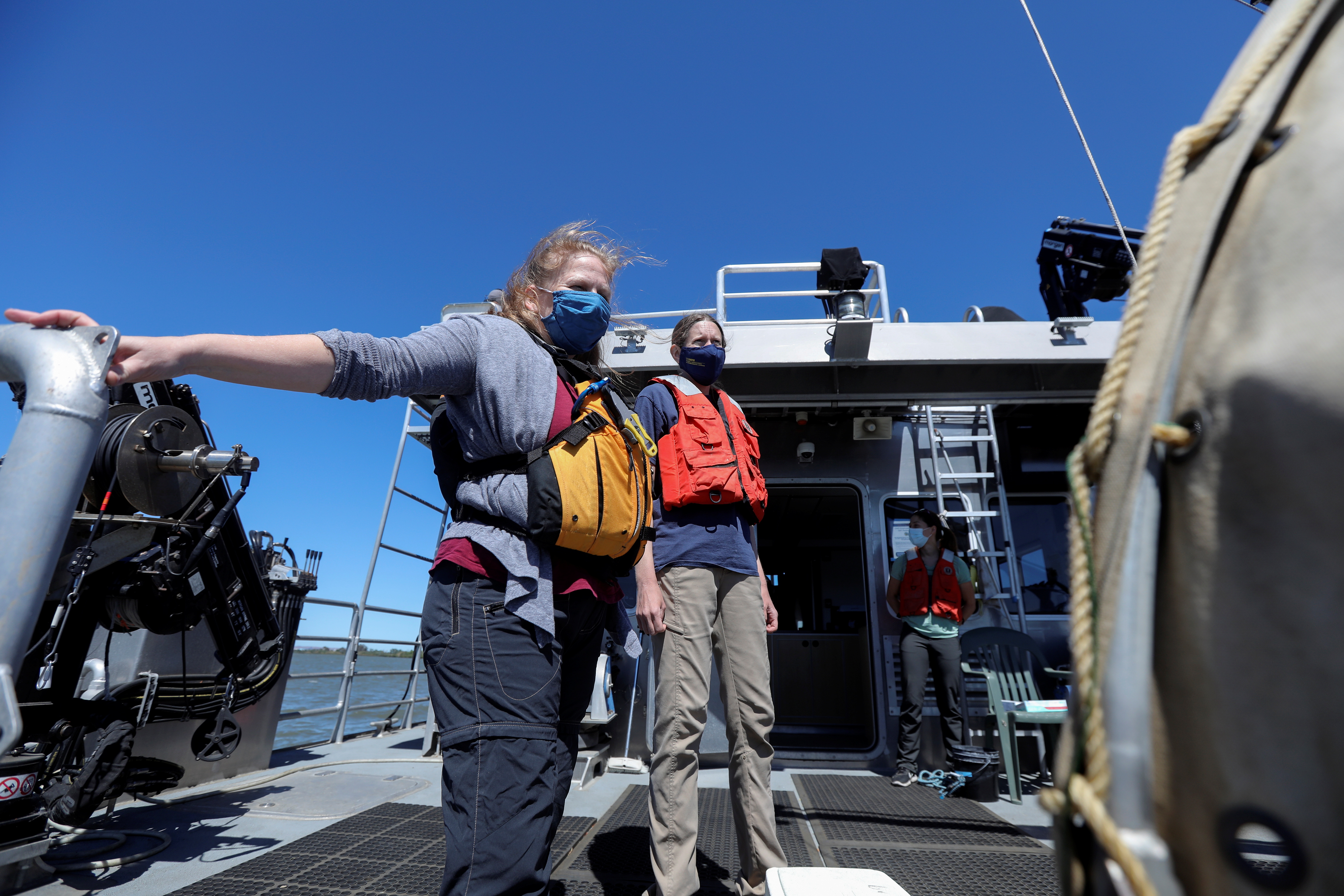 Researchers Melinda Baerwald and Andrea Schreier stand at the stern of a research vessel on the San Joaquin River off Antioch