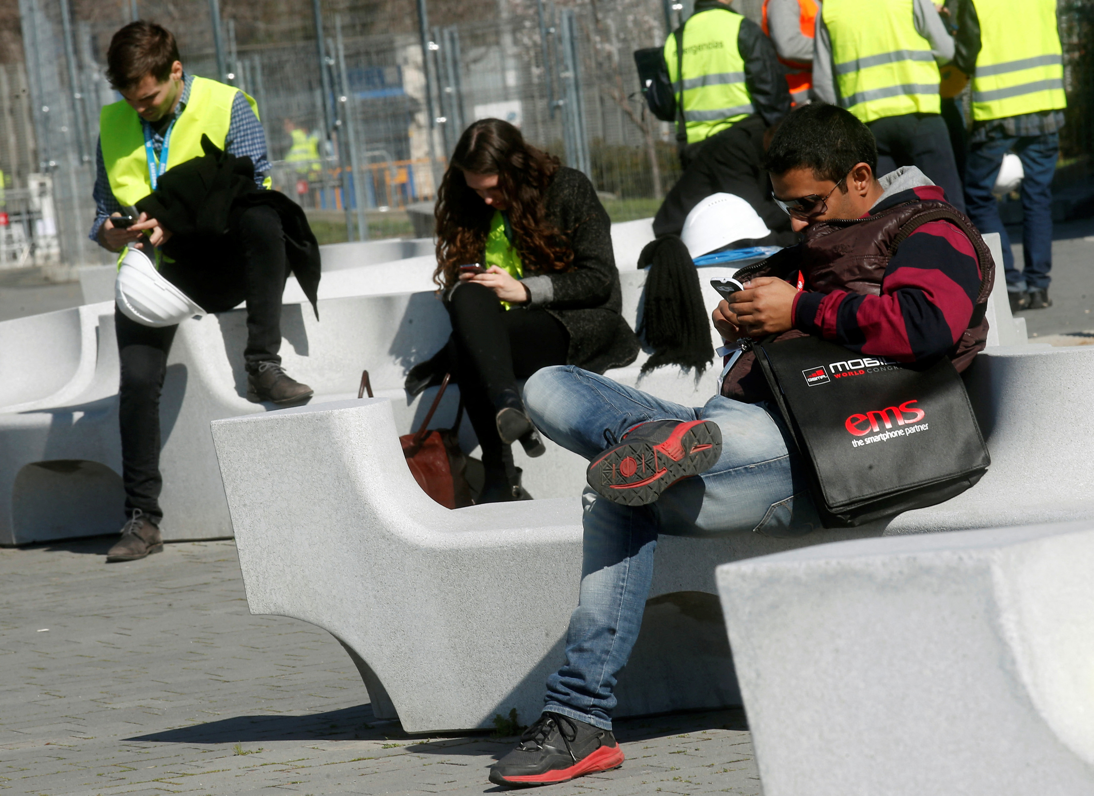 People use their mobile phones near the entrance to Mobile World Congress in Barcelona