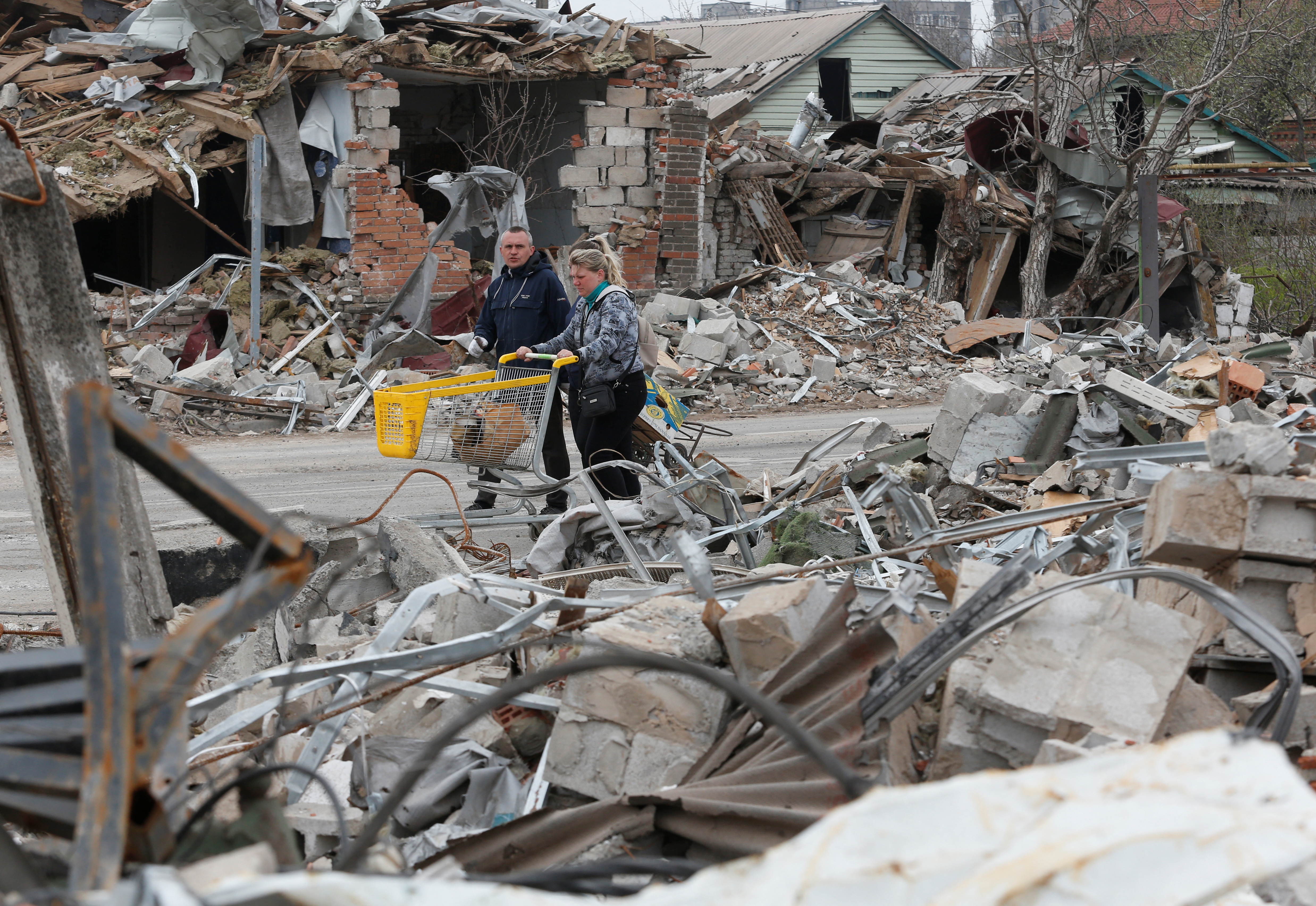Local residents walk past destroyed buildings in Mariupol