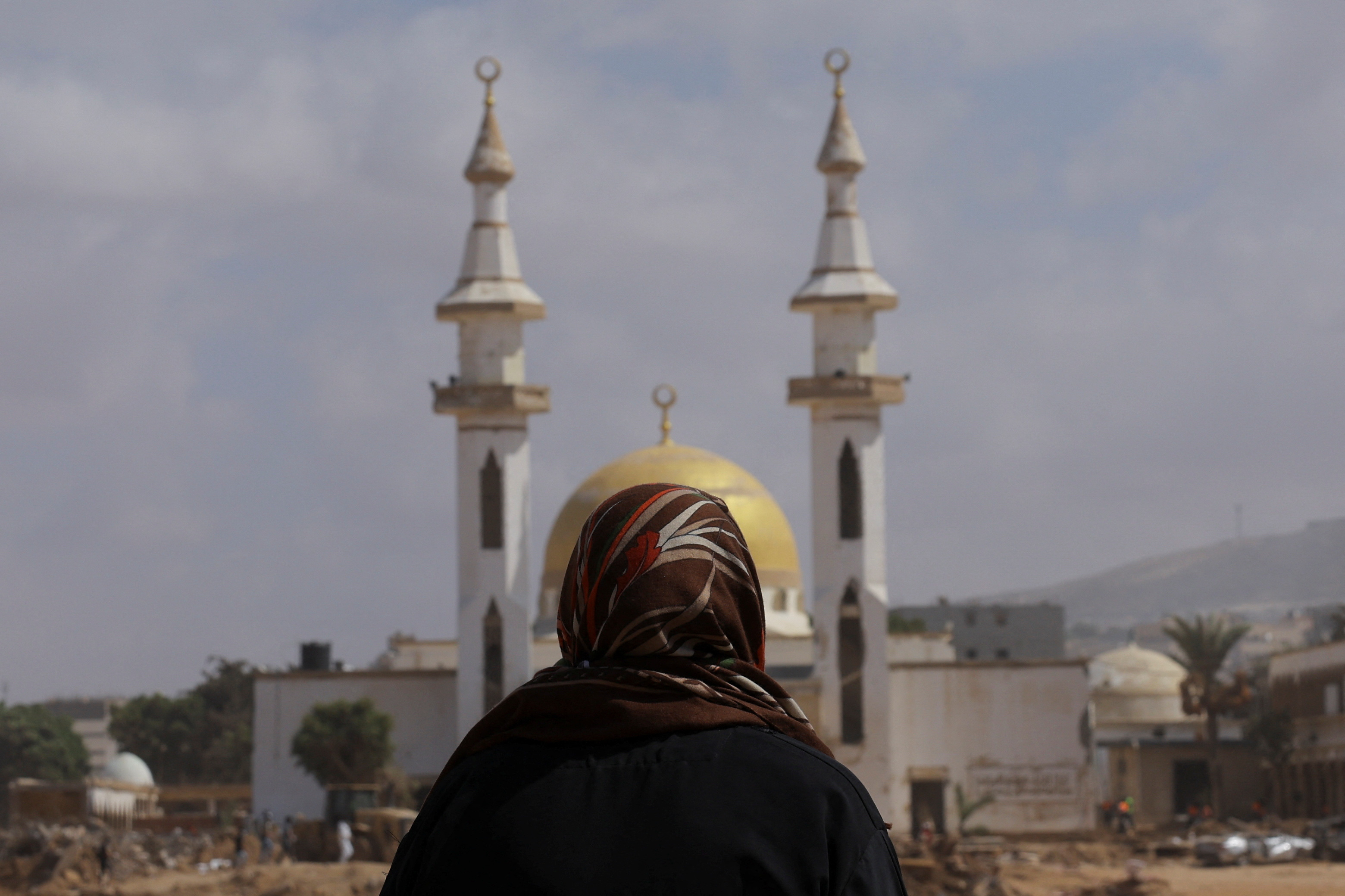 A Muslim woman prays where she says her children died during fatal floods in Derna
