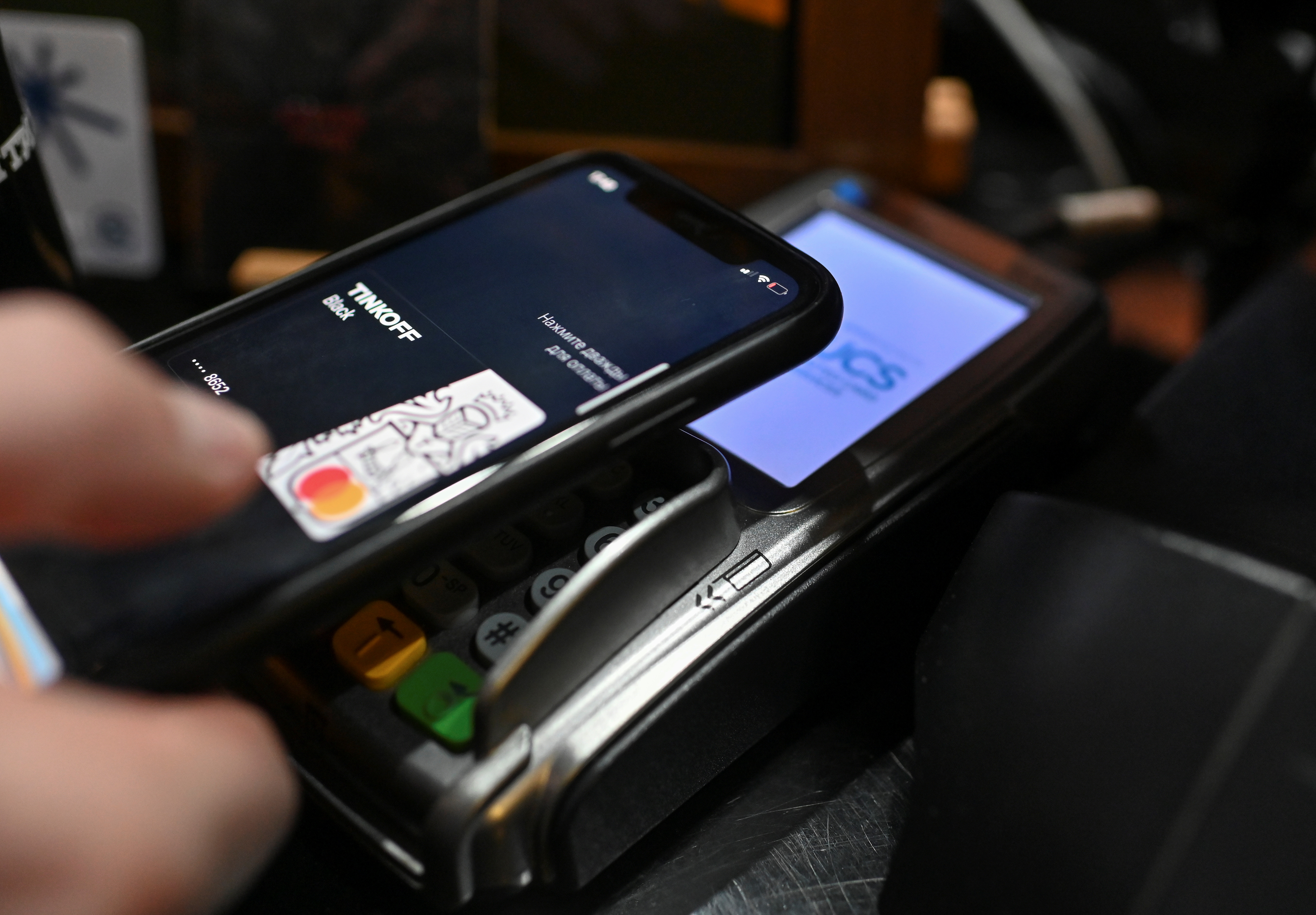 A customer uses a mobile wallet while making a purchase at a cafe in Omsk