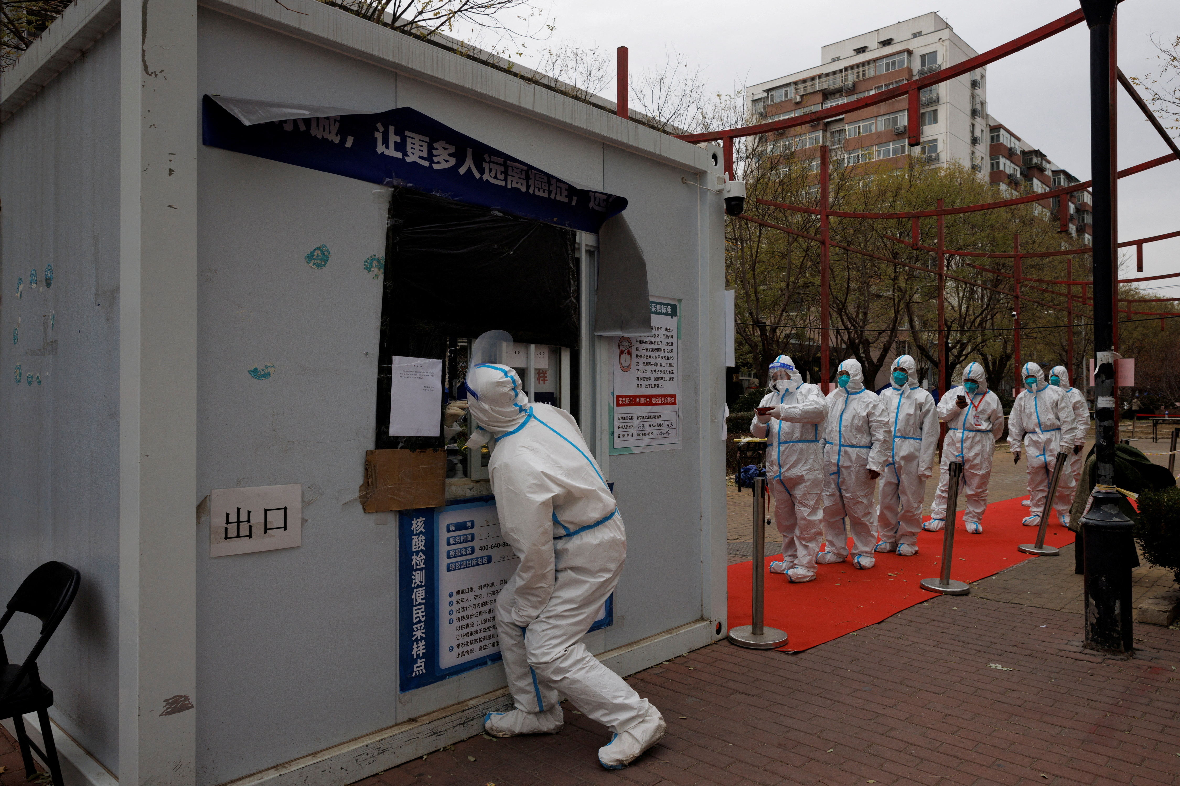 Epidemic-prevention workers in protective suits line up to get swab tested as COVID-19 outbreaks continue in Beijing