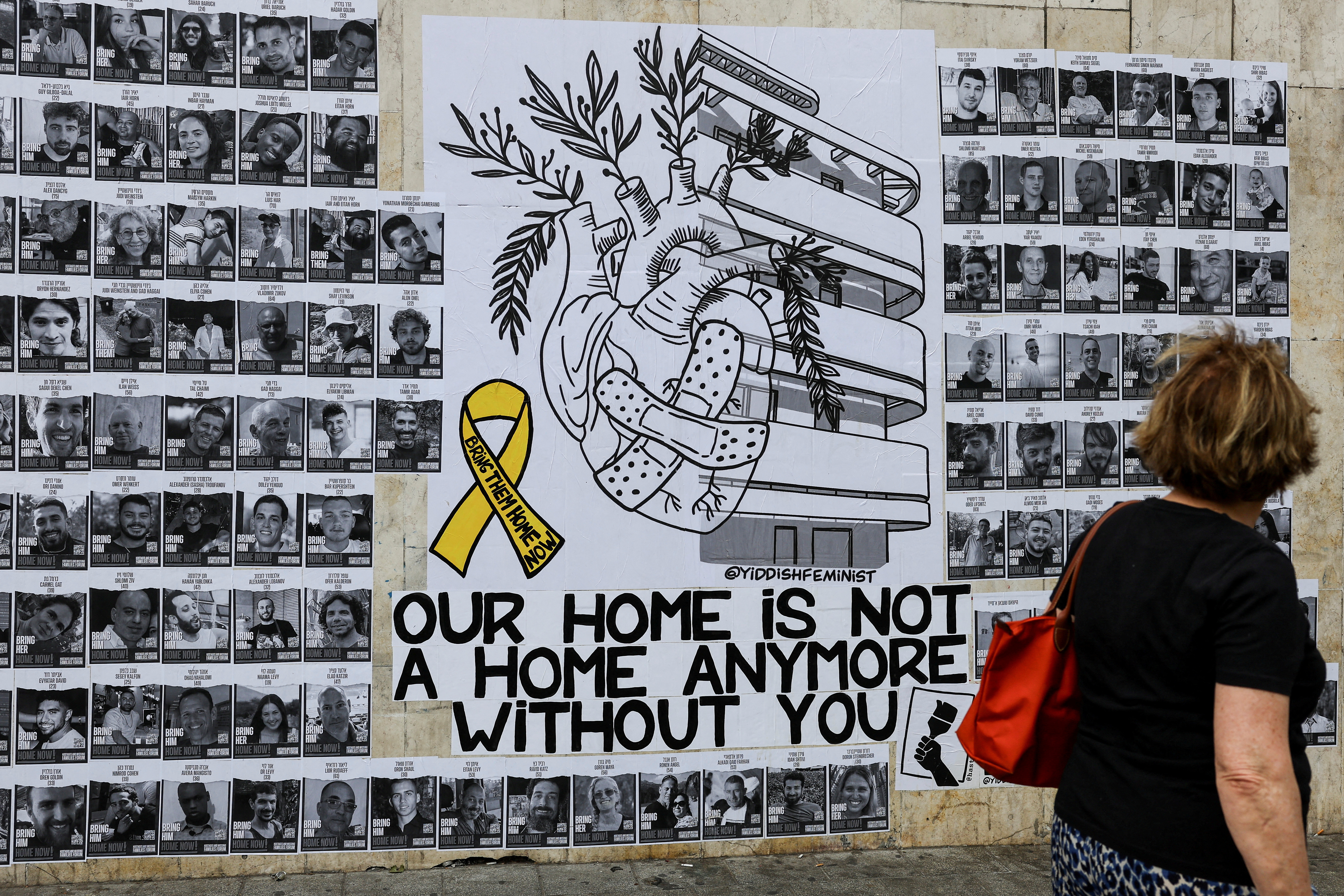 A woman looks at a wall of posters with pictures of hostages kidnapped in the deadly October 7 attack by Hamas, in Tel Aviv