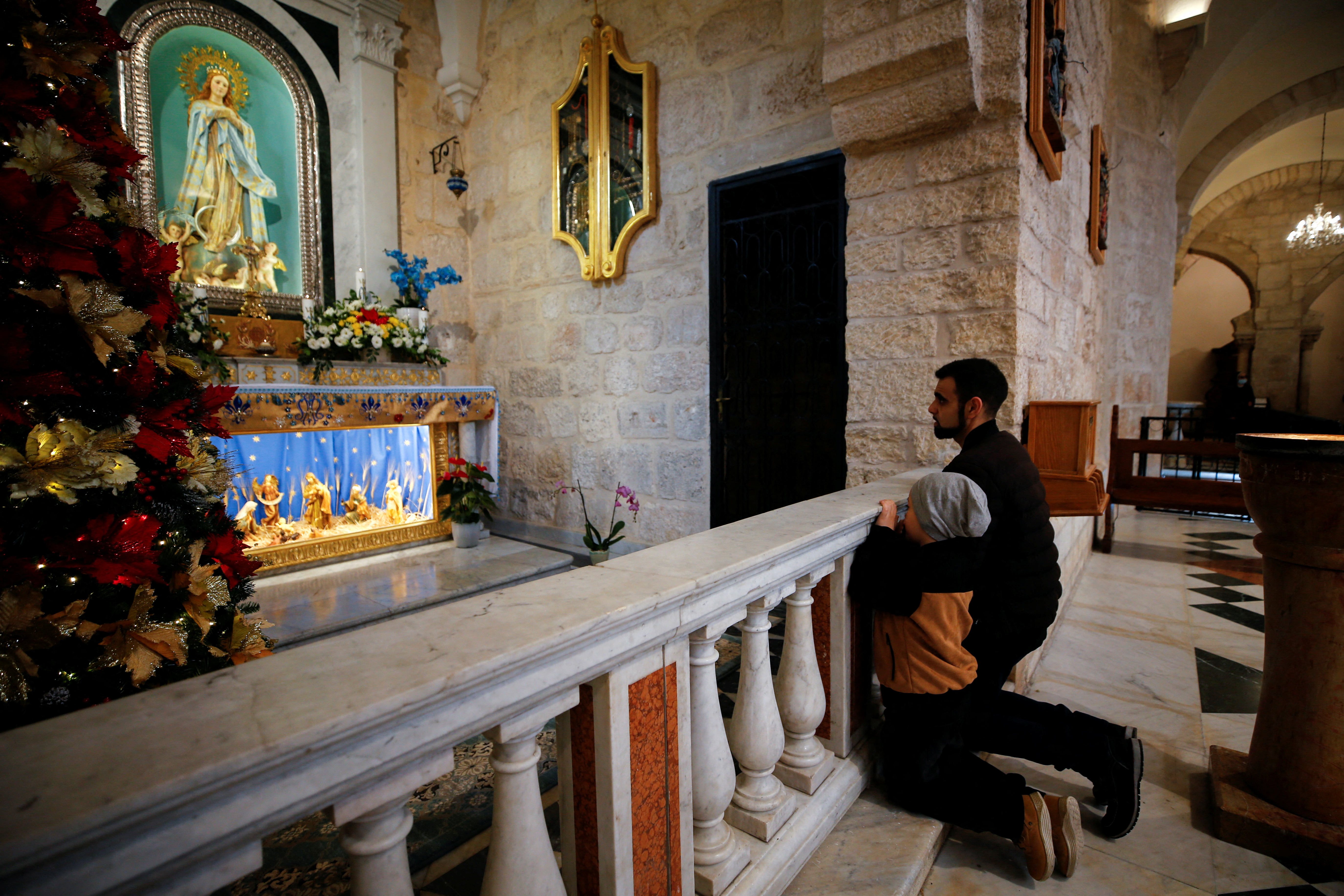 Worshipers pray ahead of Christmas morning mass at Saint Catherine's Church, in the Church of the Nativity, in Bethlehem in the Israeli-occupied West Bank, December 25, 2021. REUTERS/Mussa Qawasma