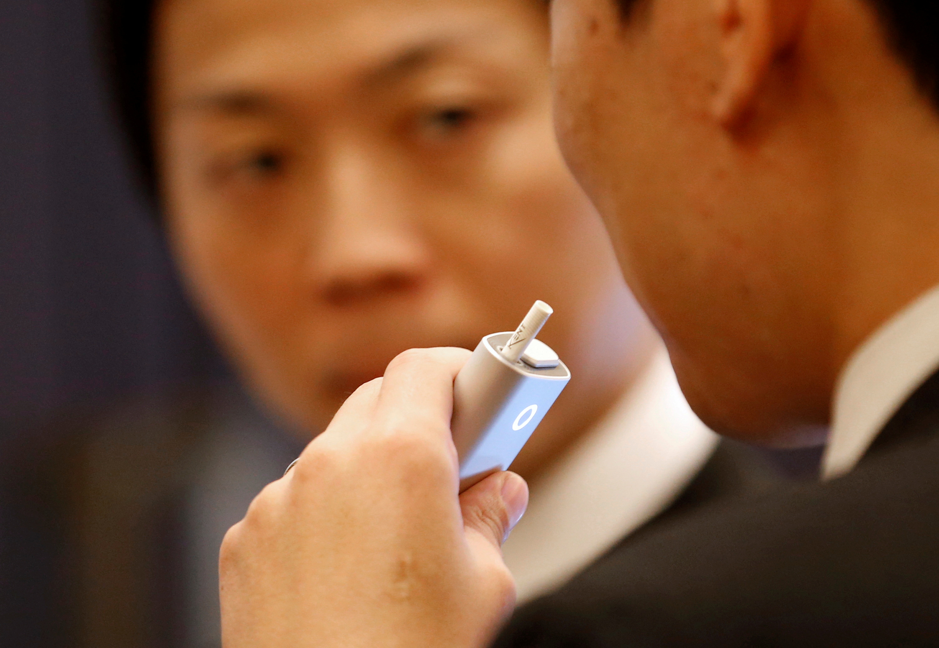 Attendees try British American Tobacco's new tobacco heating system device 'glo' after a news conference in Tokyo
