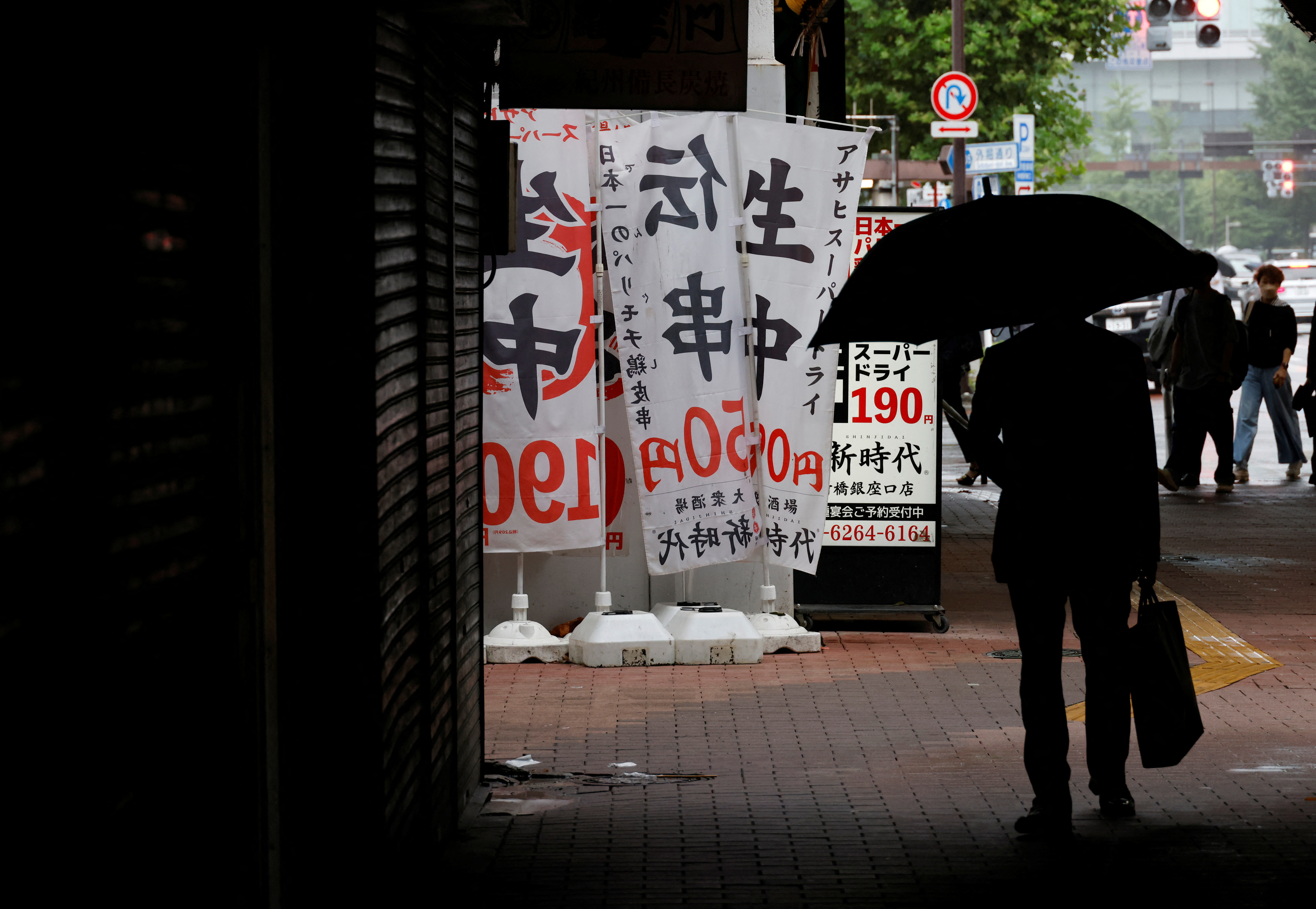 A man walks past a restaurant at a business district in Tokyo