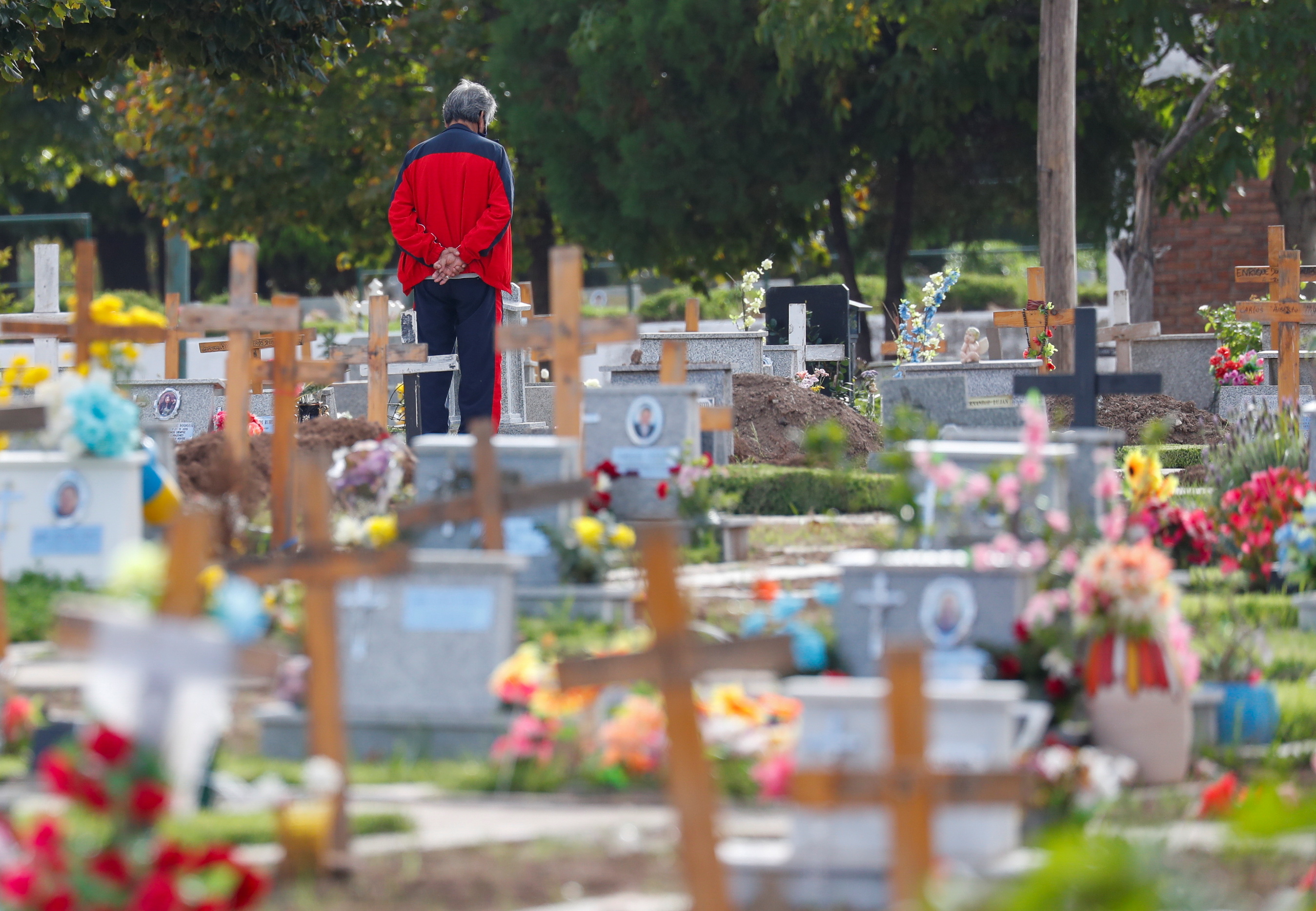 A man stands next to a grave at the Flores cemetery, amid the outbreak of the coronavirus disease (COVID-19) in Buenos Aires, Argentina April 21, 2021. REUTERS/Agustin Marcarian
