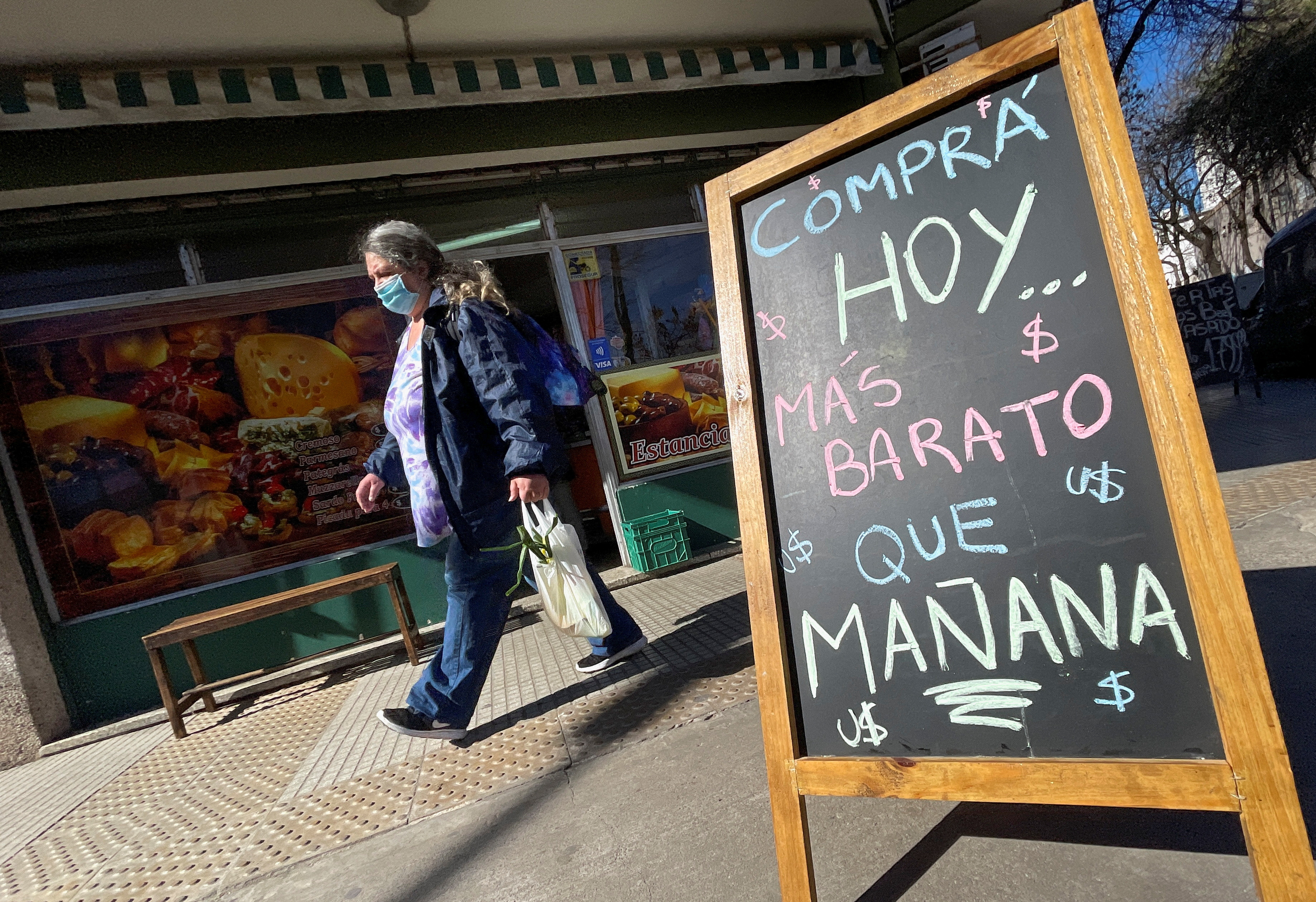 A shopper walks past a placard that reads "Buy today, cheaper than tomorrow", following Argentina's high inflation, as the economic crisis grips, in Buenos Aires