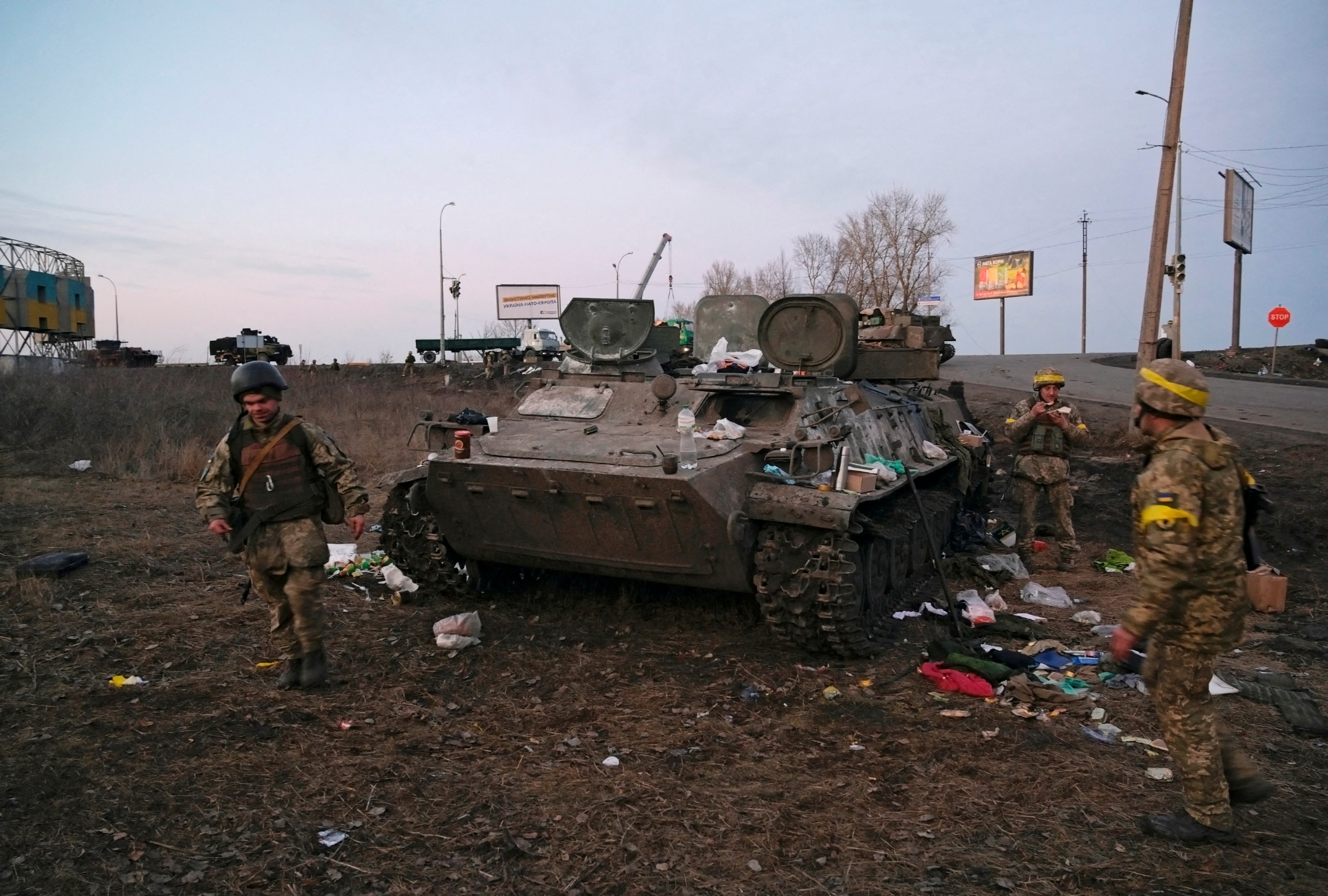 Ukrainian servicemen are seen next to a destroyed armoured vehicle, which they said belongs to the Russian army, outside Kharkiv, Ukraine February 24, 2022. REUTERS/Maksim Levin