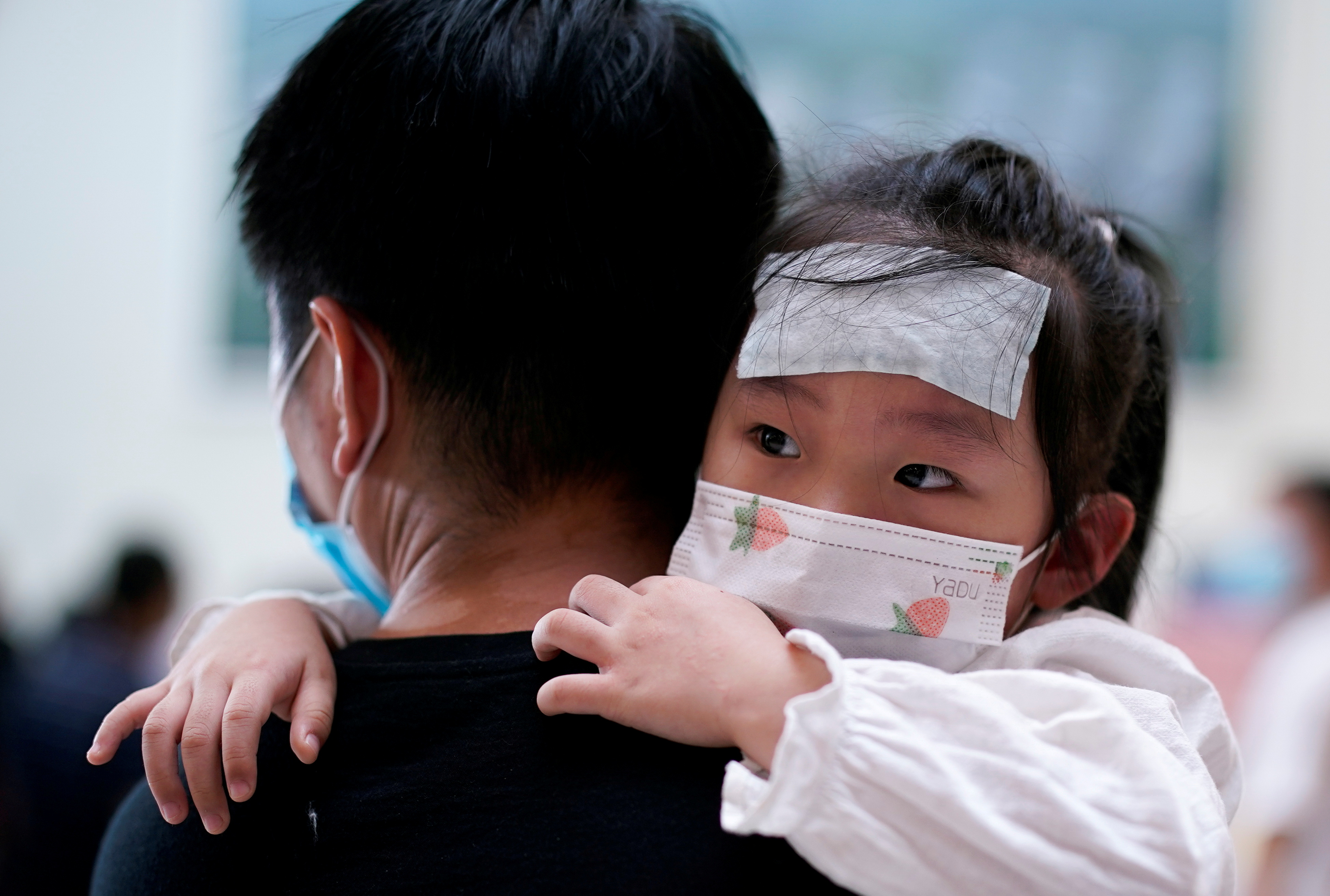 A man carries a child wearing a face mask during a government organised media tour at Tongji Hospital following the coronavirus disease (COVID-19) outbreak, in Wuhan, Hubei province, China September 3, 2020. REUTERS/Aly Song/File Photo