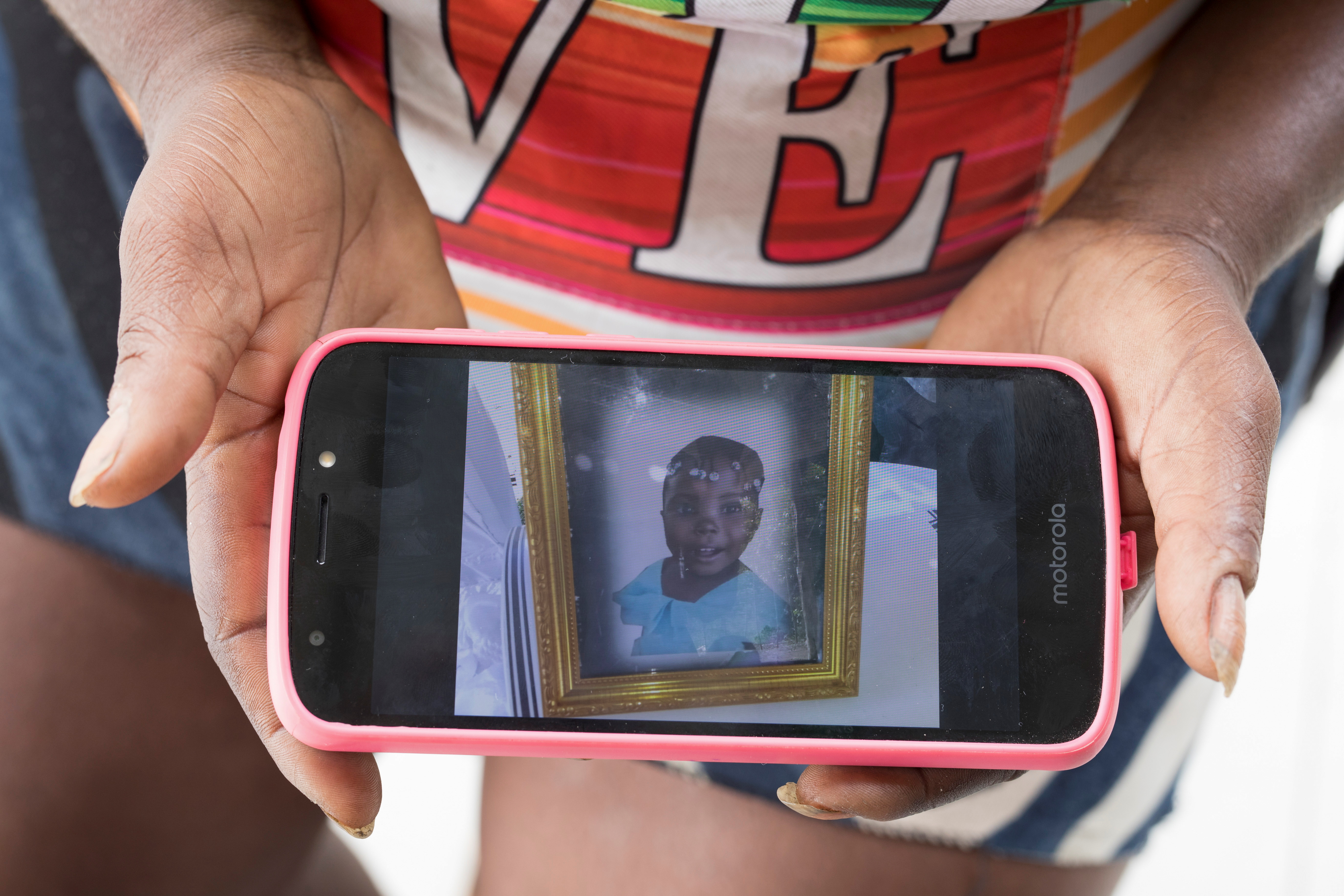 A woman who works as a peanut vendor and wants to remain anonymous, shows a photo of her five-year-old daughter Olslina Janneus, who was kidnapped at her poor neighborhood and found dead days later, during an interview with Reuters in Port-au-Prince, Haiti March 9, 2021. Picture taken March 9, 2021. REUTERS/Valerie Baeriswyl