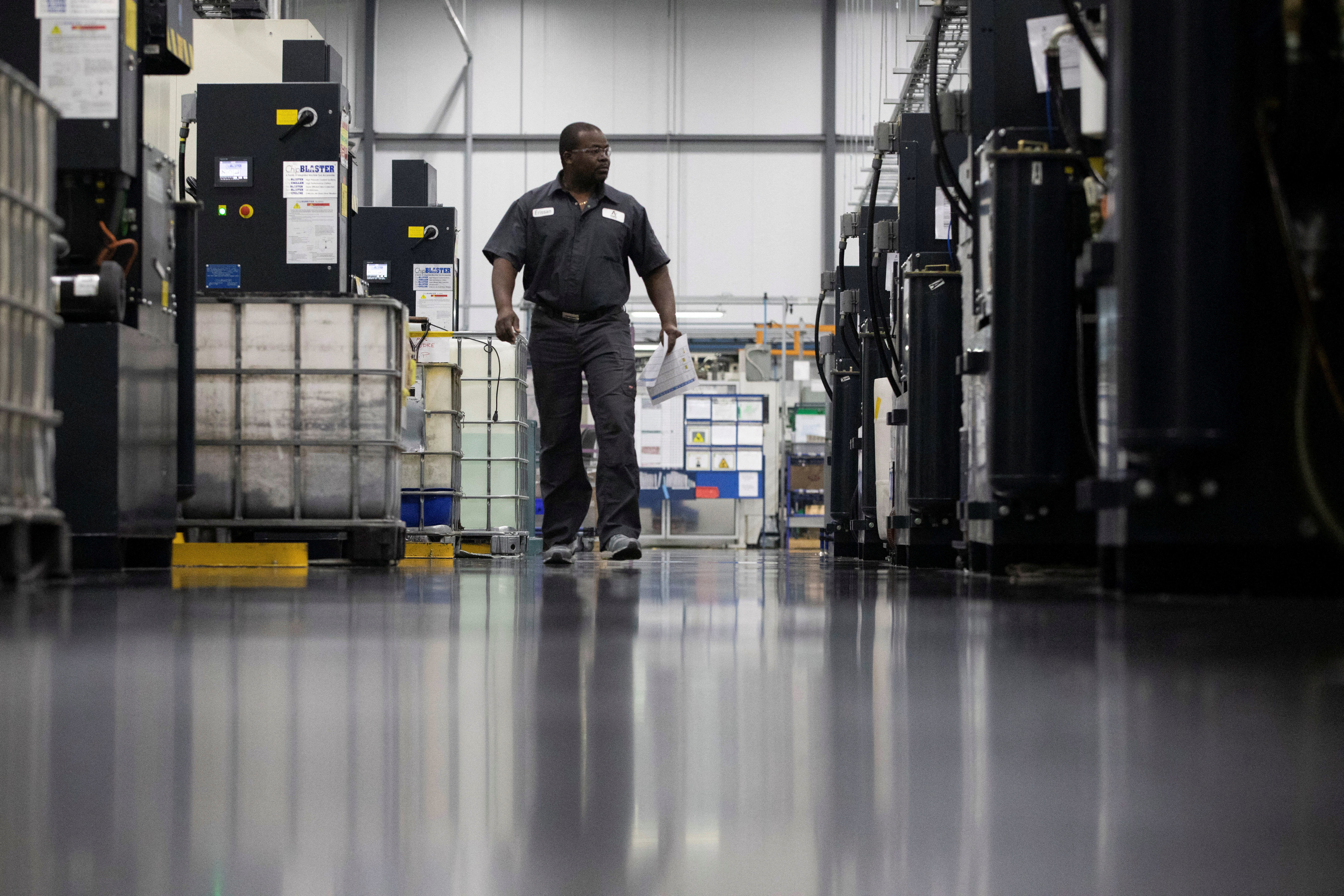 A factory worker walks past a row of automated five-axis cells used in the production and manufacturing of aircraft parts, at Abipa Canada, in Boisbriand