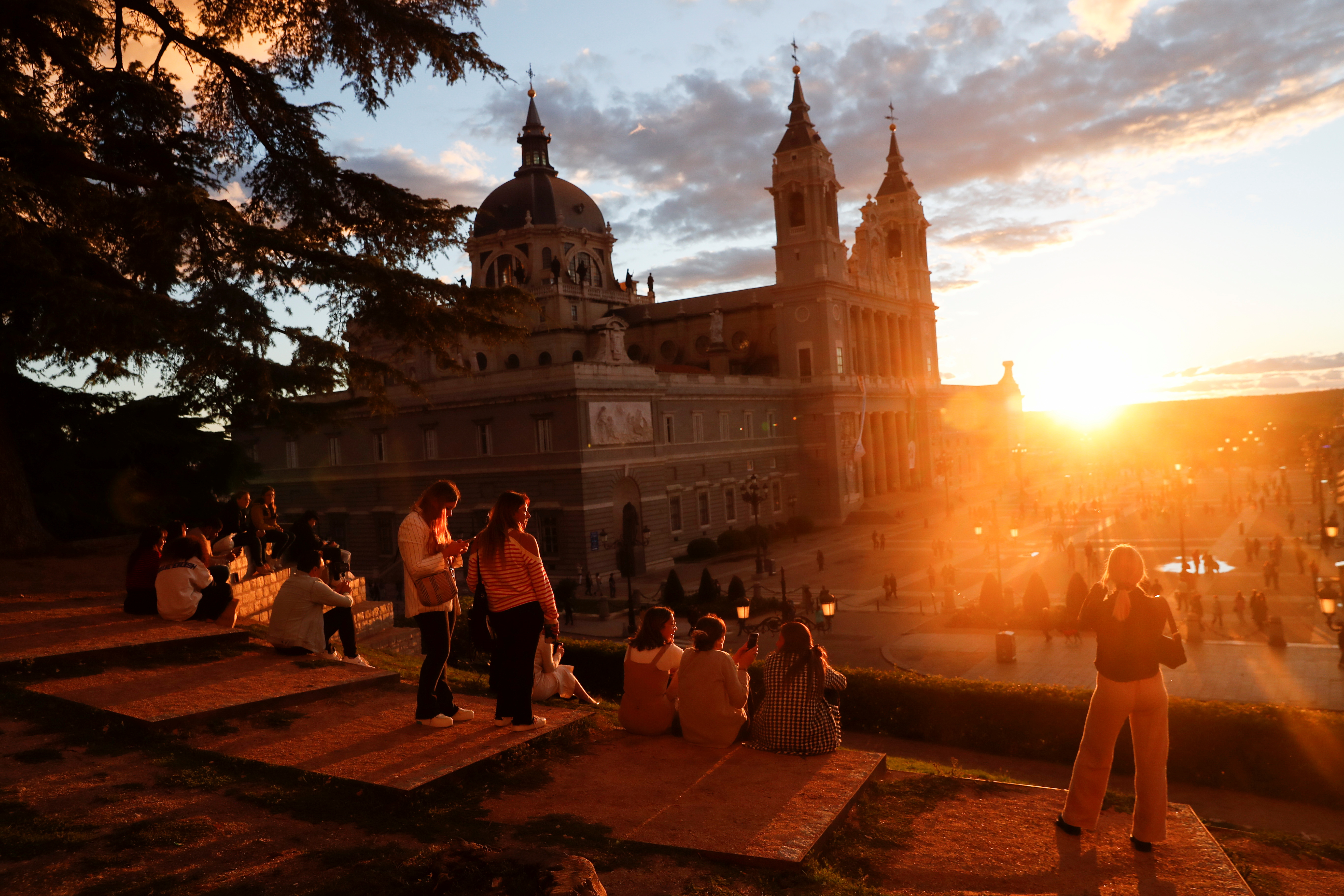 Tourists and locals watch the sunset by La Almudena Cathedral in Madrid