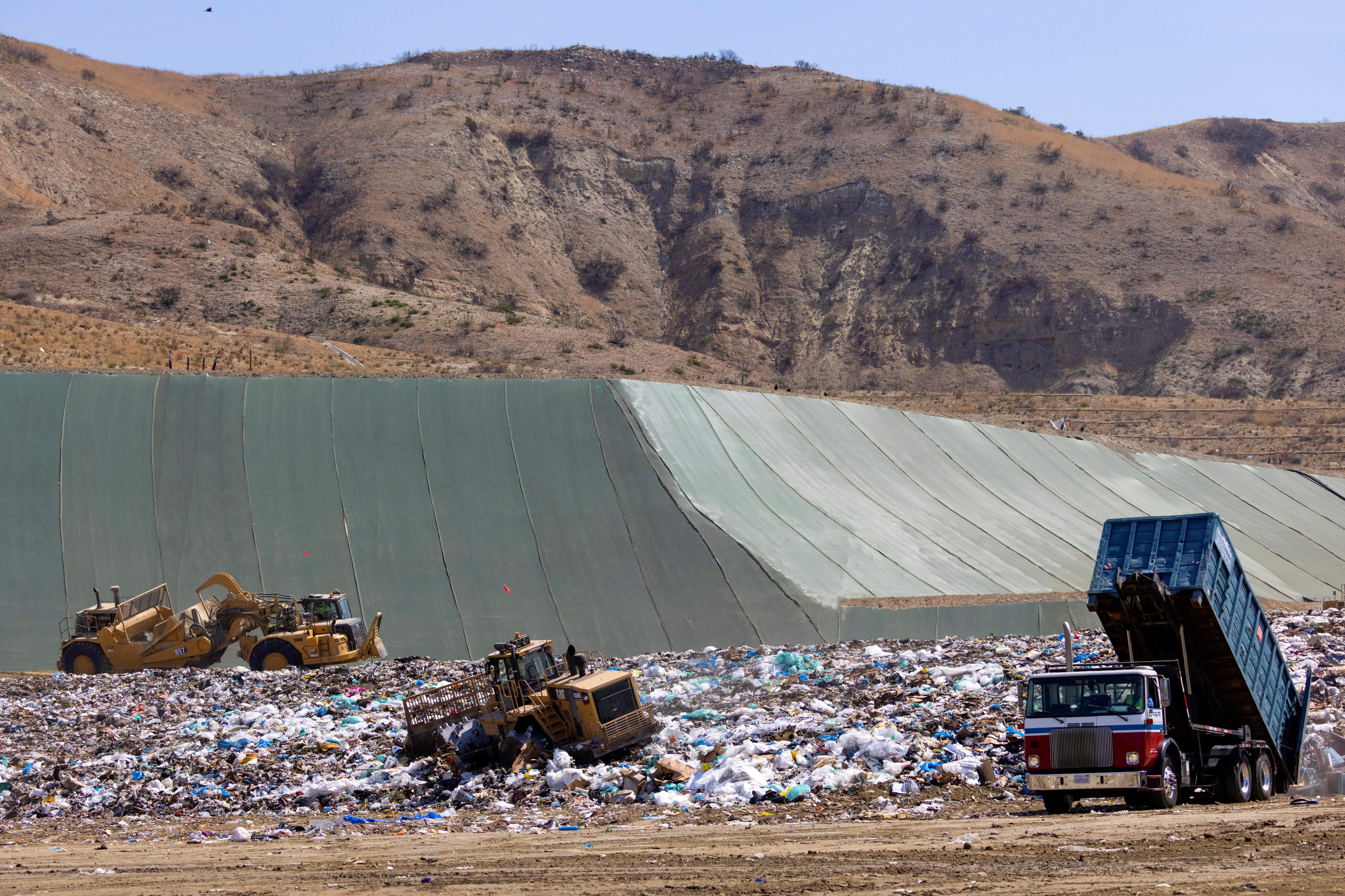 Workers use heavy machinery to move trash and waste at the Frank R. Bowerman landfill in California