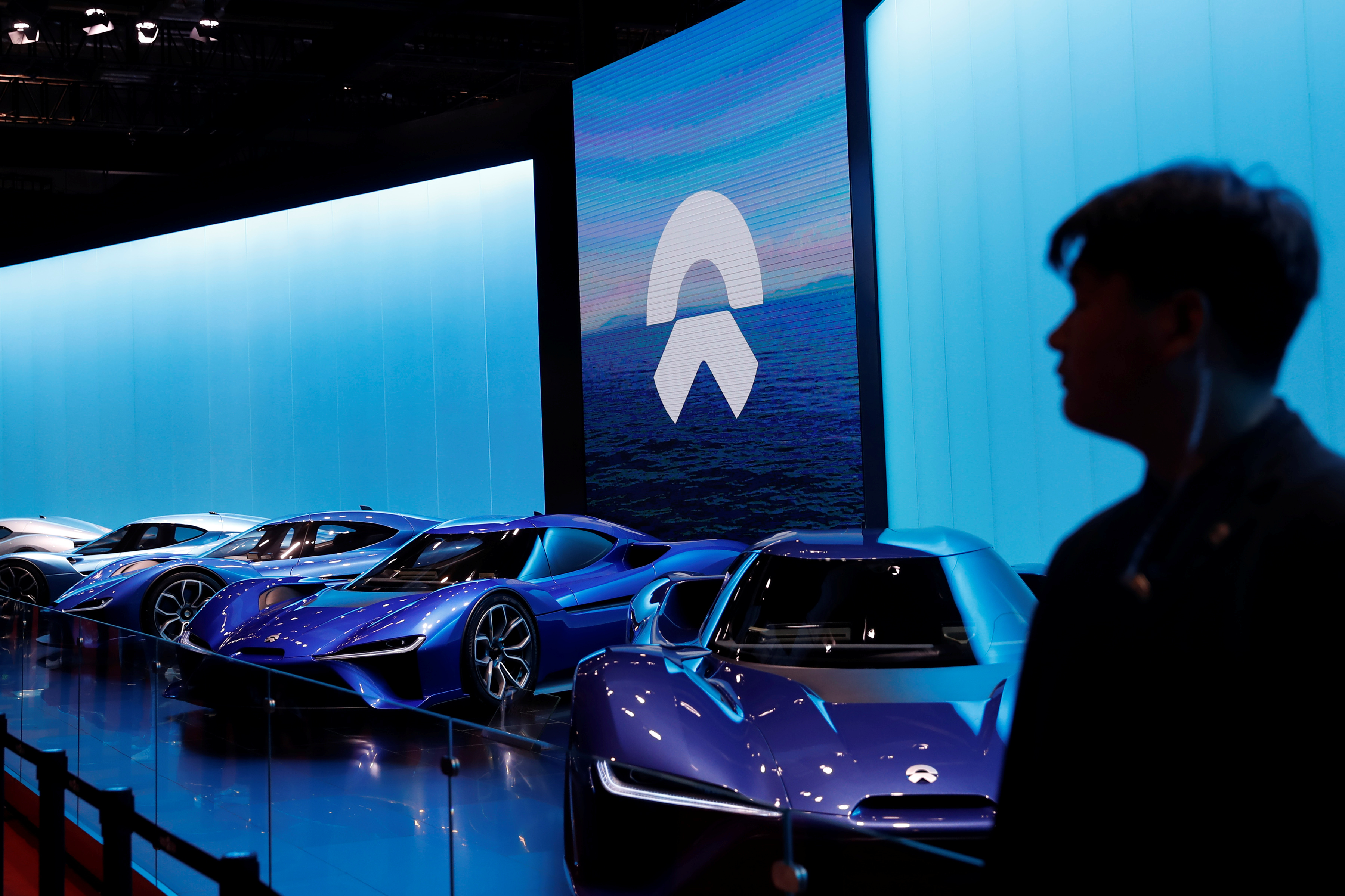 Man is silhouetted in front of Nio cars at auto show in Shanghai