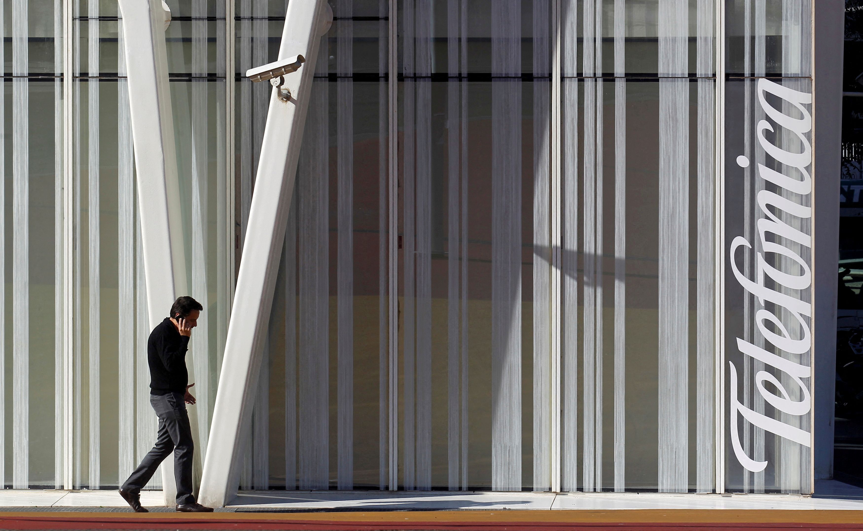 FILE PHOTO: A man speaks by a mobile next to Telefonica's tower in Barcelona