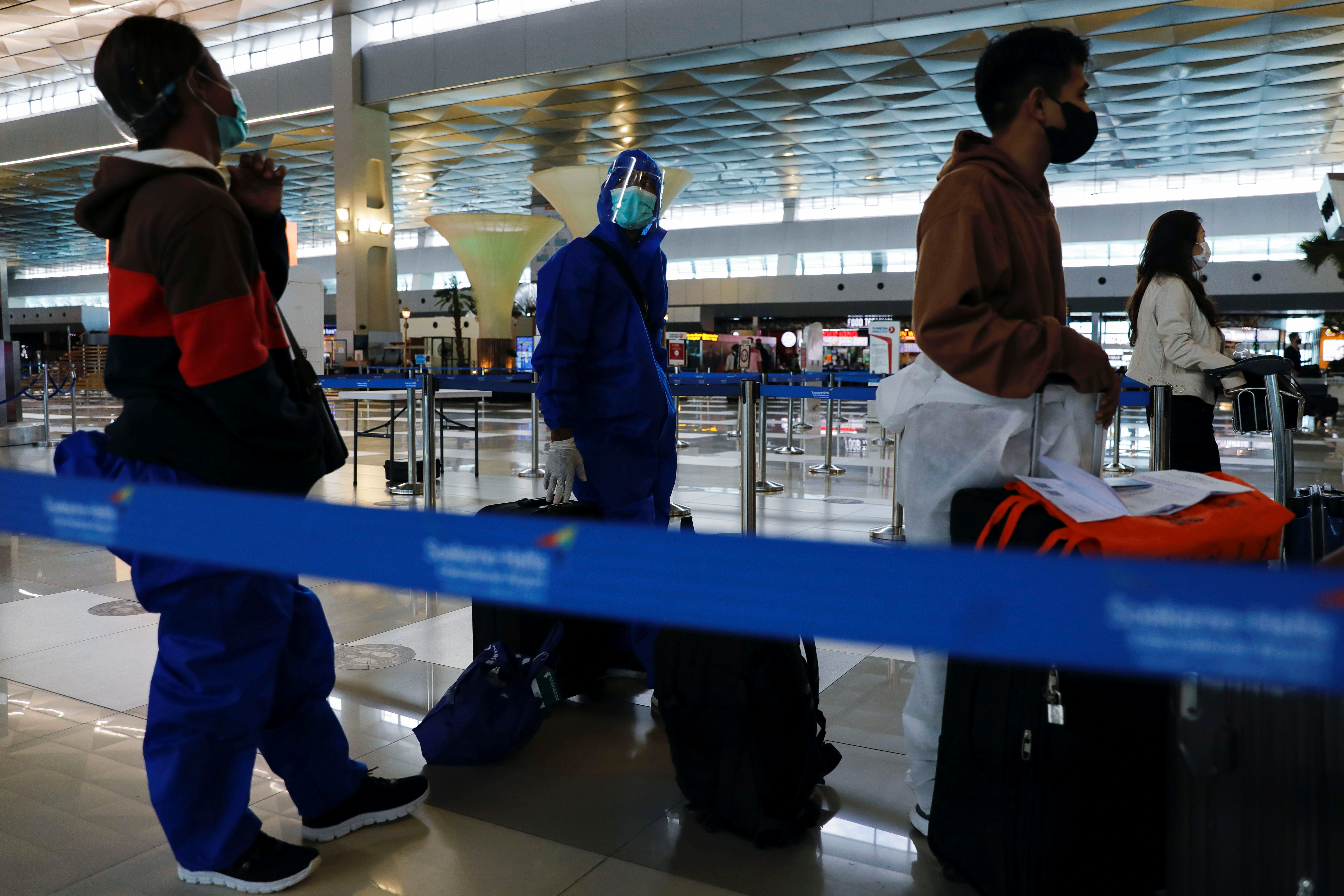 Travellers wearing protective suits are seen at the Soekarno Hatta International airport, as the country bans the arrival of travellers who have been in eight African countries to curb the spread of the new Omicron variant of the coronavirus, in Tangerang, near Jakarta, Indonesia, November 29, 2021. REUTERS/Willy Kurniawan/file photo