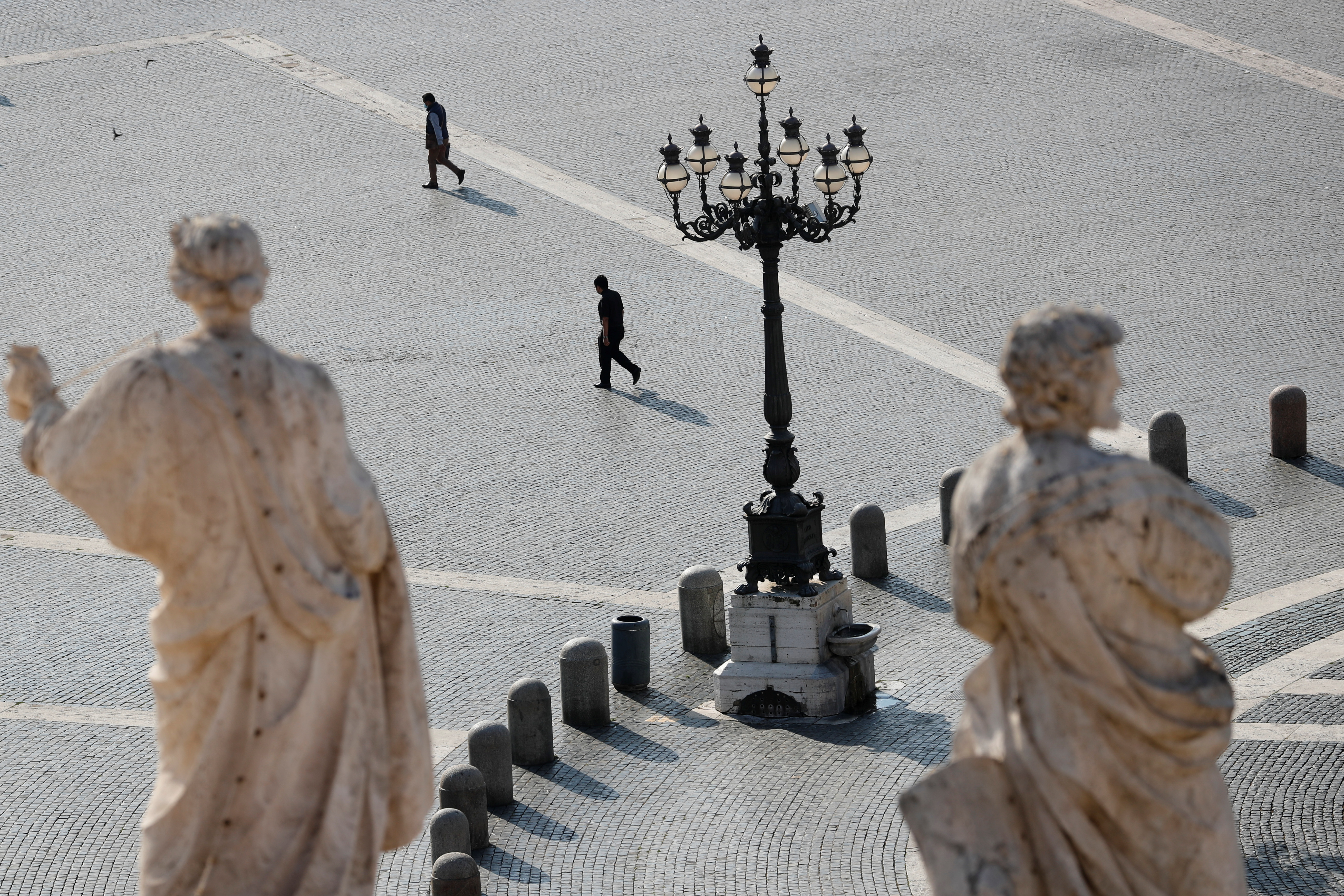 People walk in St. Peter's Square ahead of Pope Francis' weekly general audience, amid the coronavirus disease (COVID-19) pandemic, at the Vatican, June 9, 2021. REUTERS/Remo Casilli
