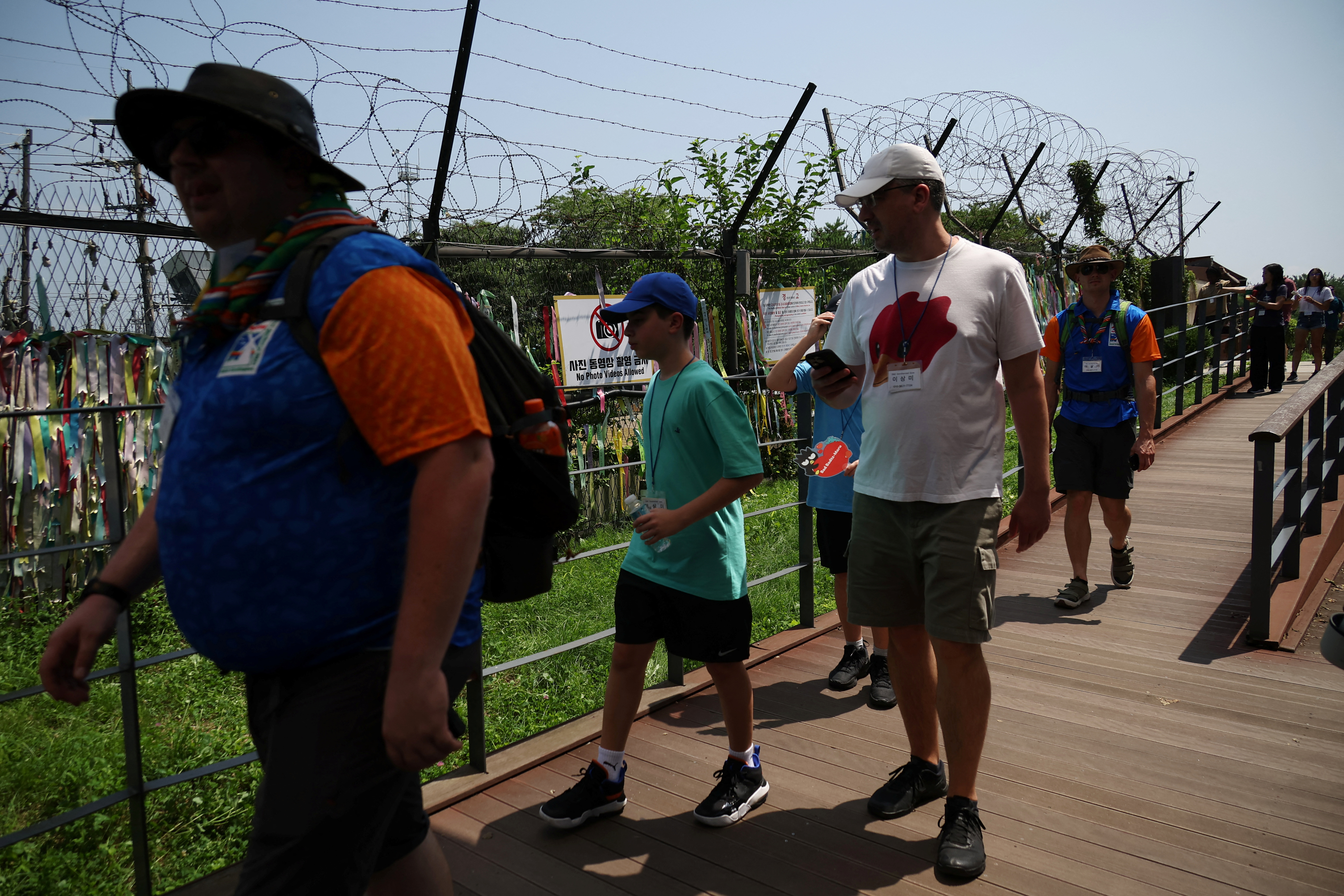 Foreign tourists participating in DMZ tour walk past a military fence near the demilitarized zone separating the two Koreas, in Paju