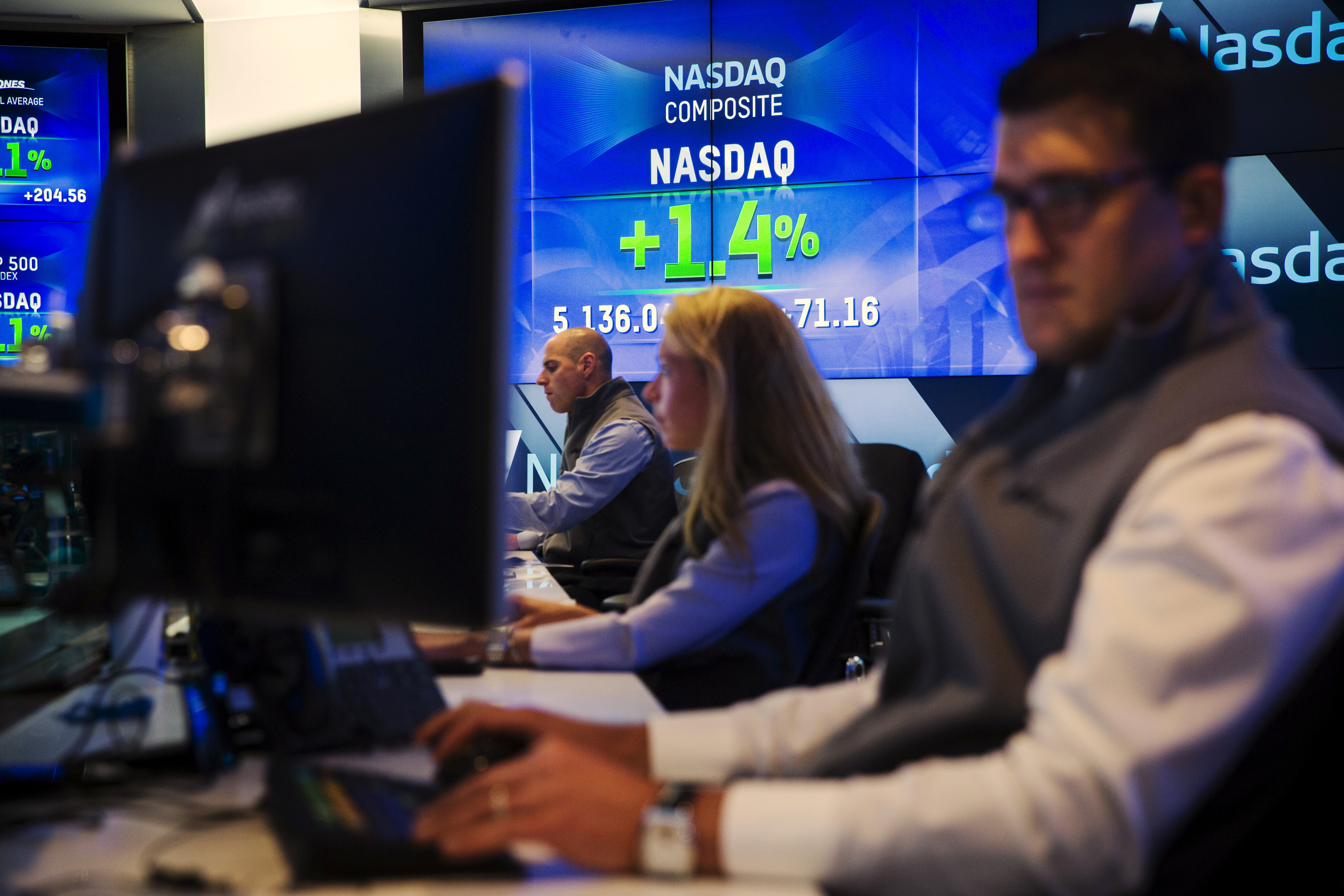Traders work at their desks at the Nasdaq MarketSite in New York