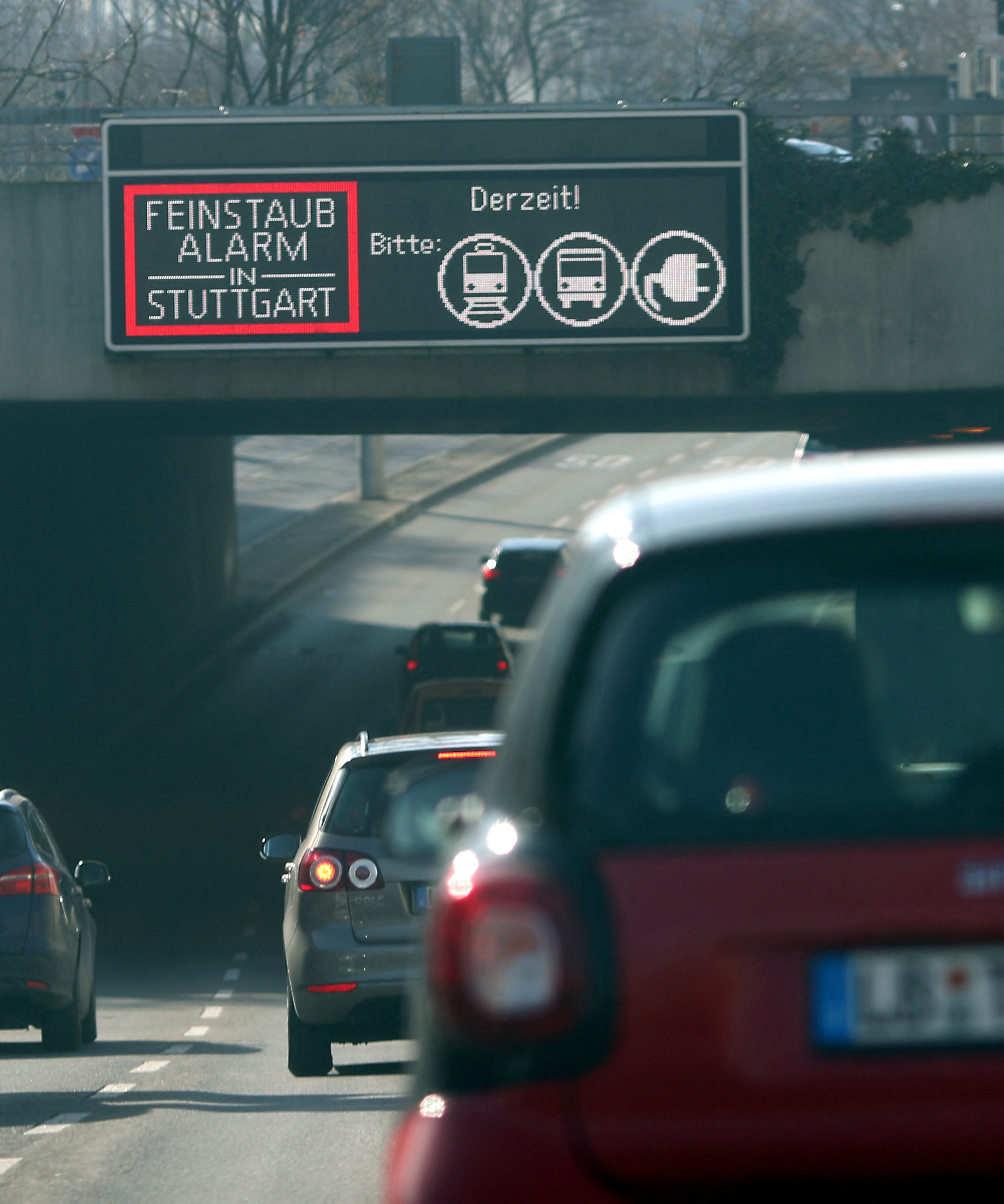 Cars pass a sign alerting about fine particulates on a busy street in downtown Stuttgart